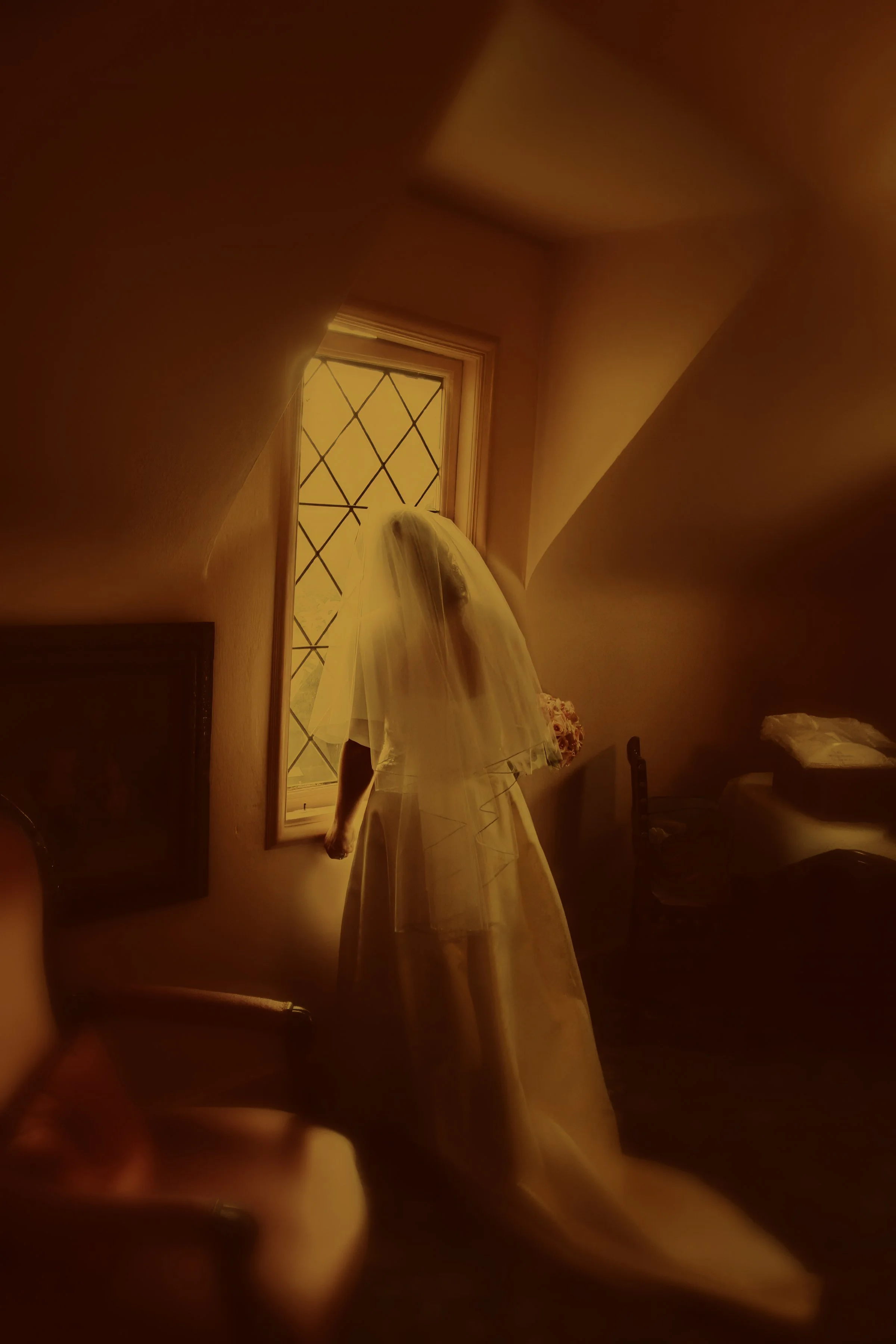 Bride peers out the window of the bridal suite in an elegant fine art photograph at Saint Clements Castle.