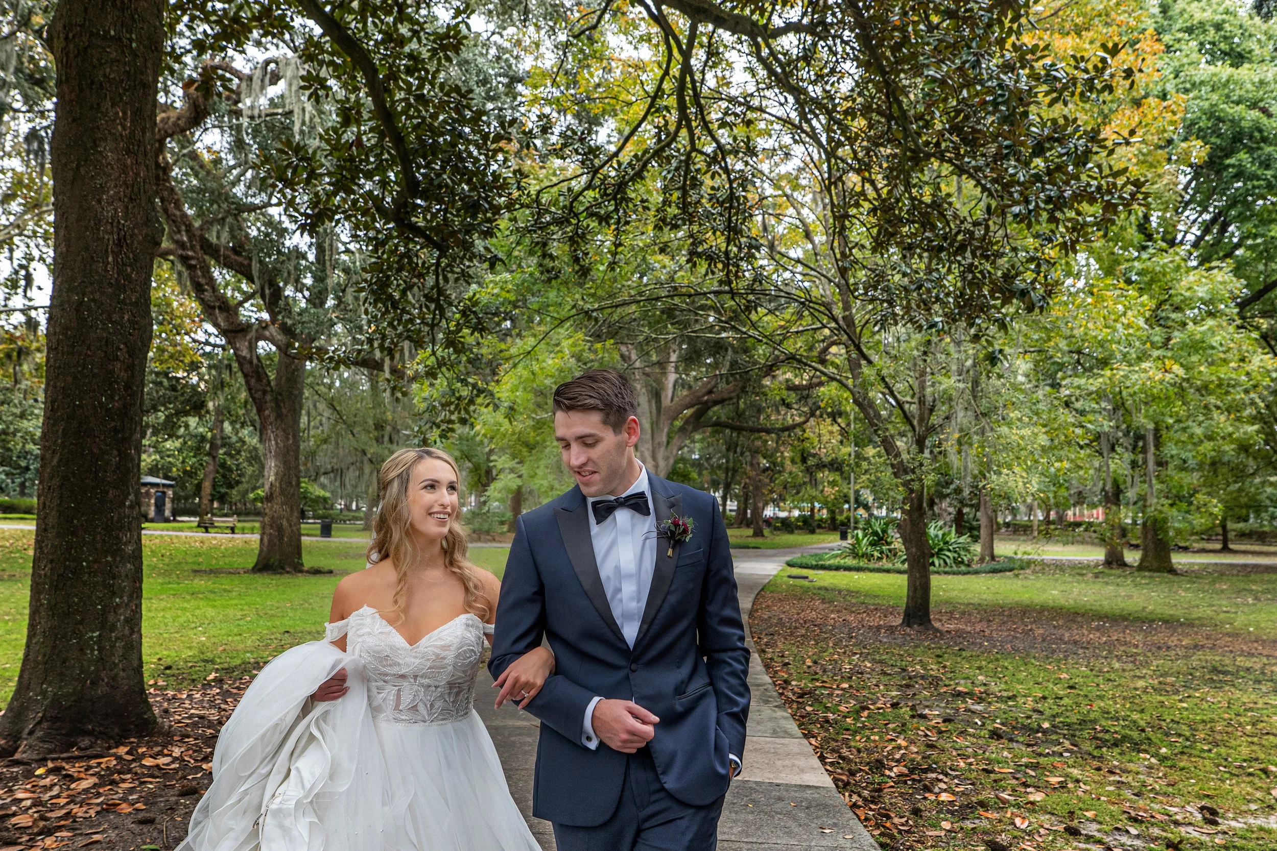 Arm and arm the bride and groom walk joyfully through Forsyth Park