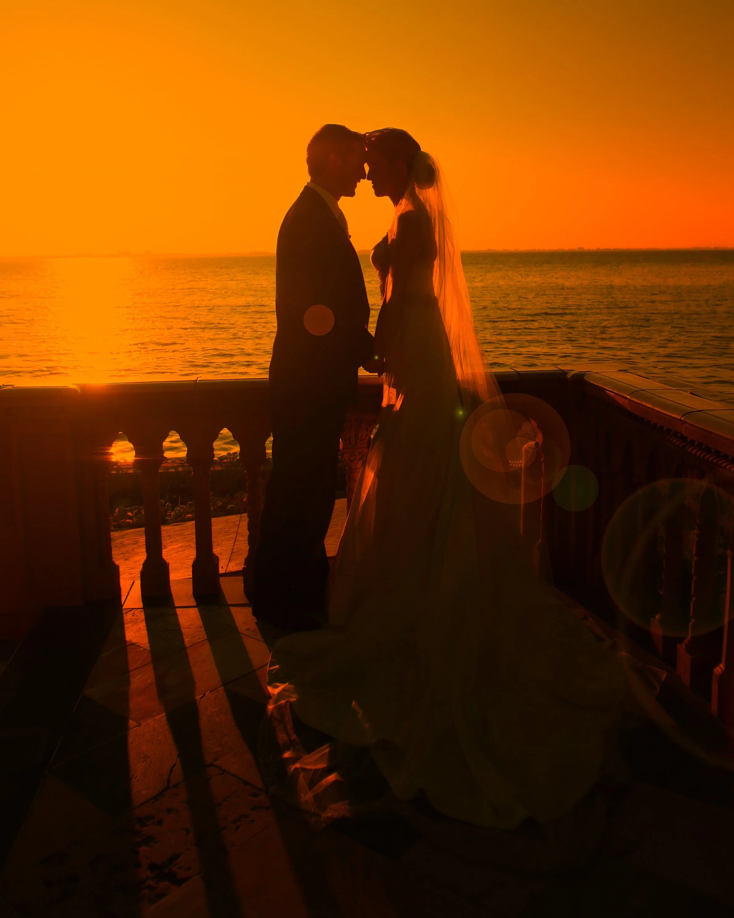 Bride and groom embrace at sunset on Sarasota Bay, Ringling Museum wedding
