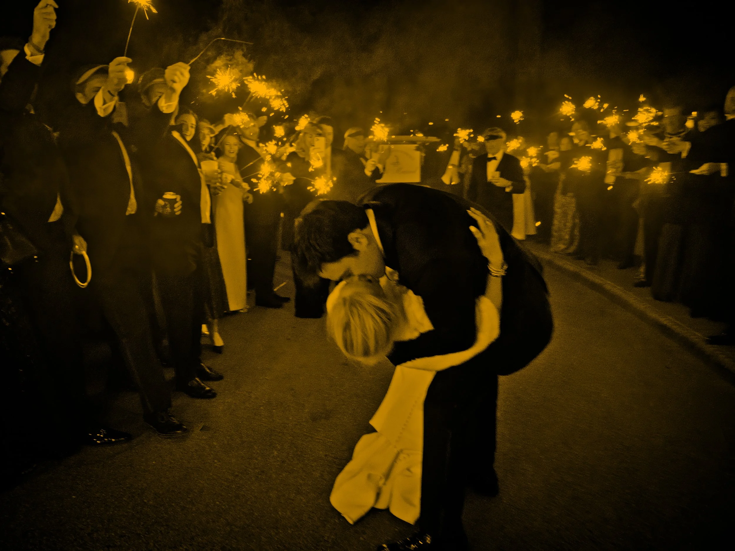 Groom dips the bride as guests cheer during their sparkler send-off at a Pinehurst Resort wedding.