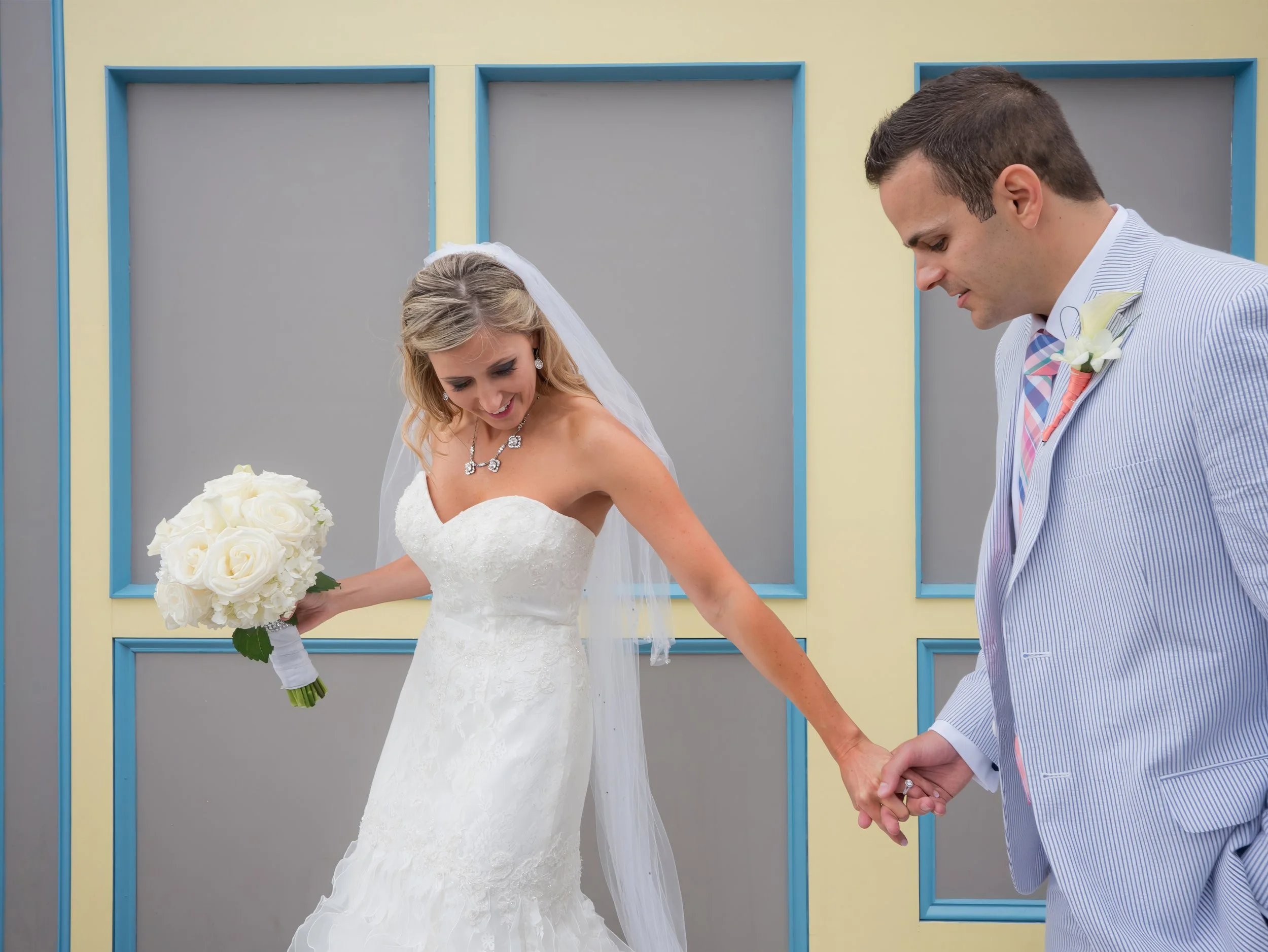 Bride and groom walk hand in hand through the colorful streets of Newport Rhode Island on the way to The Bohlin.