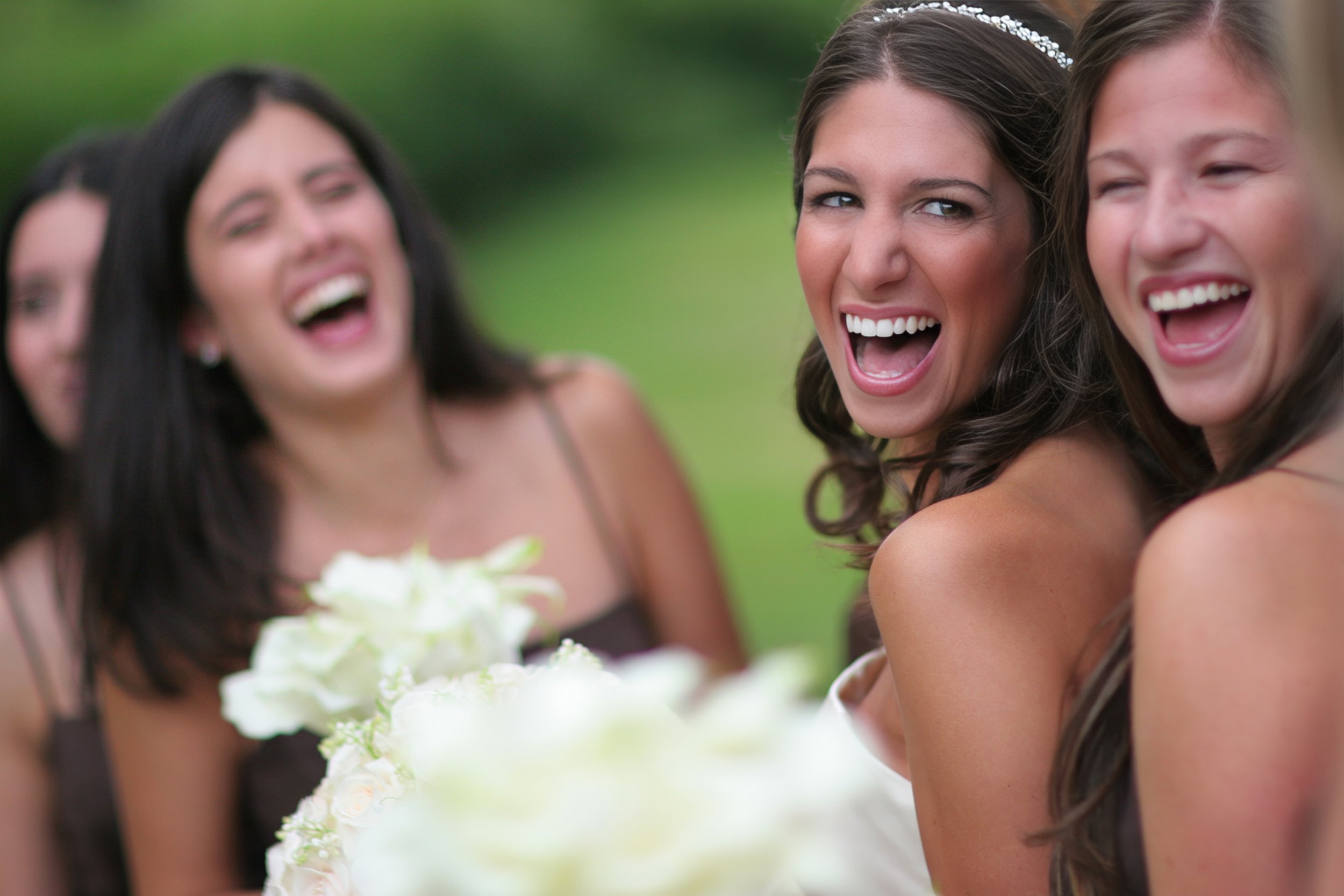Bride and friends laugh together on the wooded grounds of Tappan Hill in the Hudson Valley.