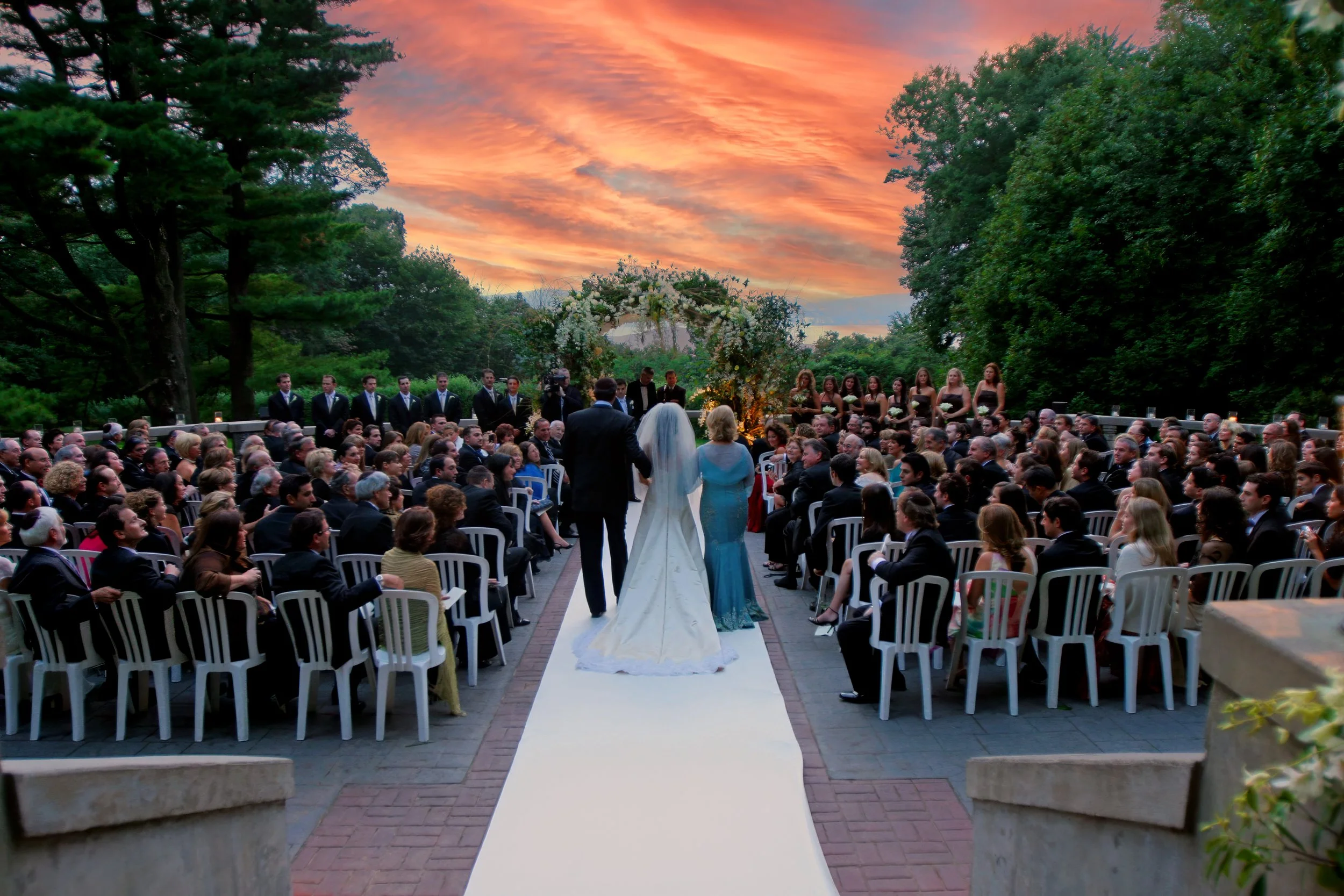 Bride escorted by her parents down the aisle during a terrace wedding ceremony at Tappan Hill overlooking the Hudson Valley.