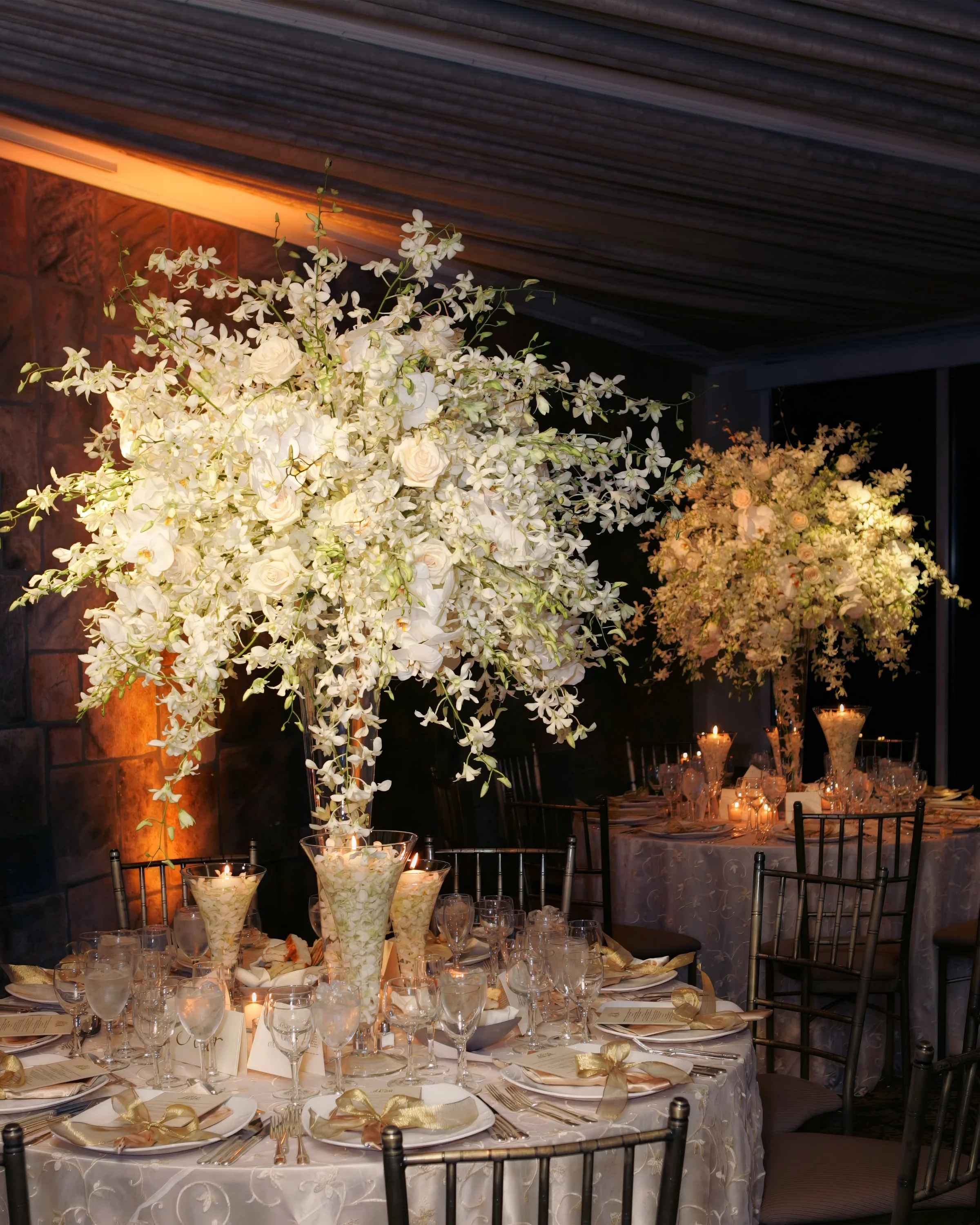 Tall, elegant floral centerpieces on tables in the Tappan Hill Ballroom prepared for a luxurious wedding reception.