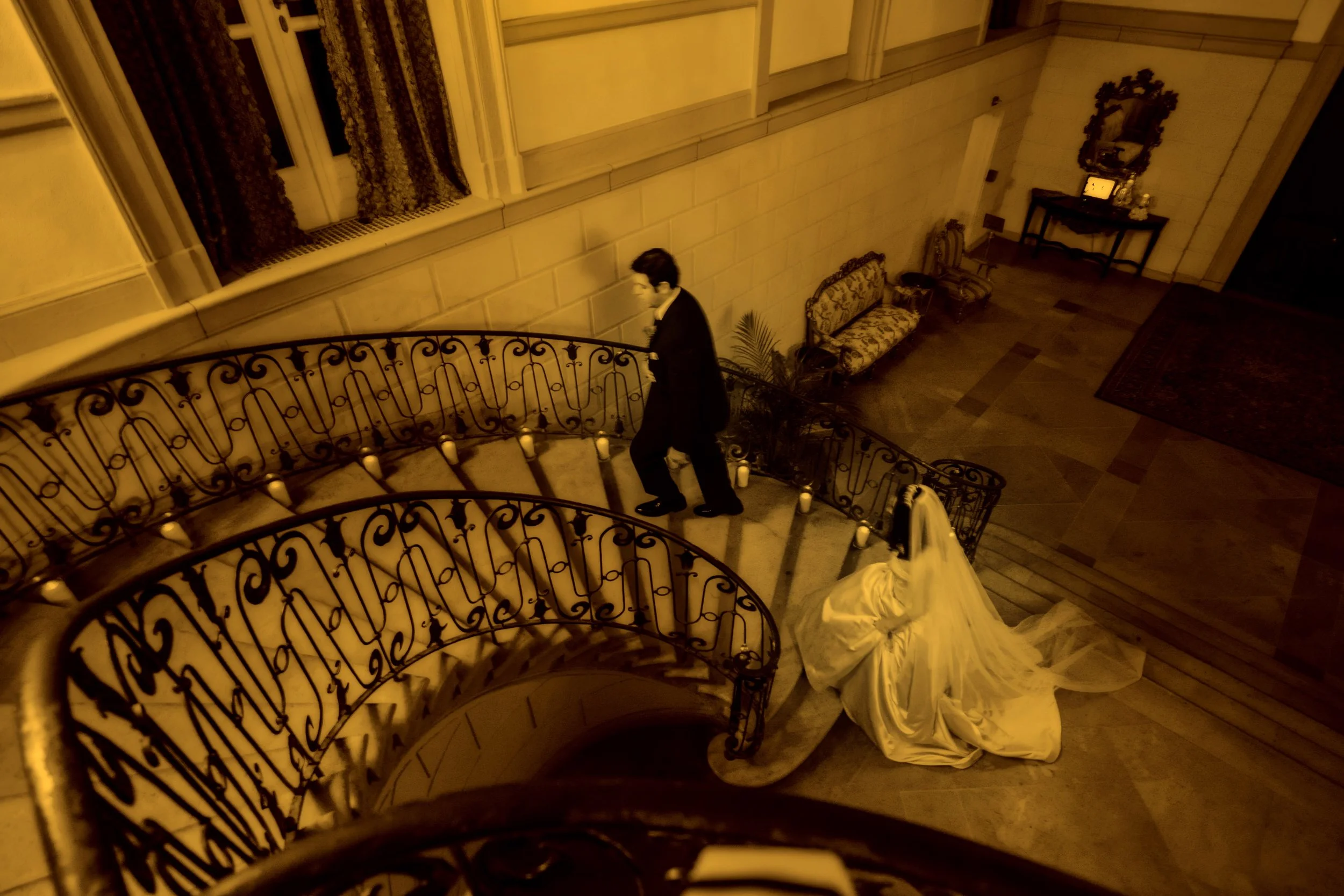 Bride and groom walking up the grand staircase in the foyer at Oheka Castle during their wedding day