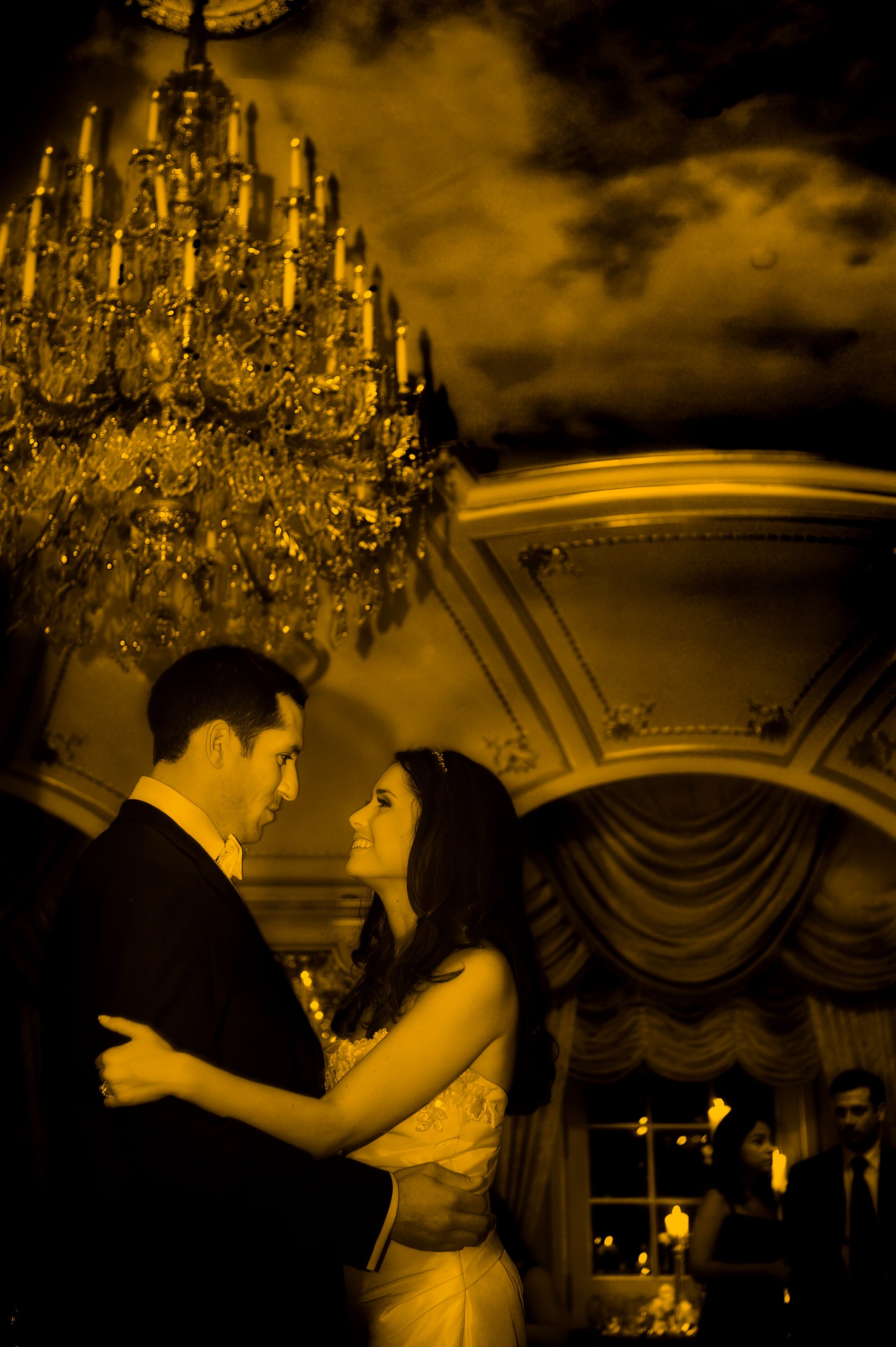 Bride and groom sharing a romantic moment beneath the chandeliers in the ballroom at The St. Regis New York.