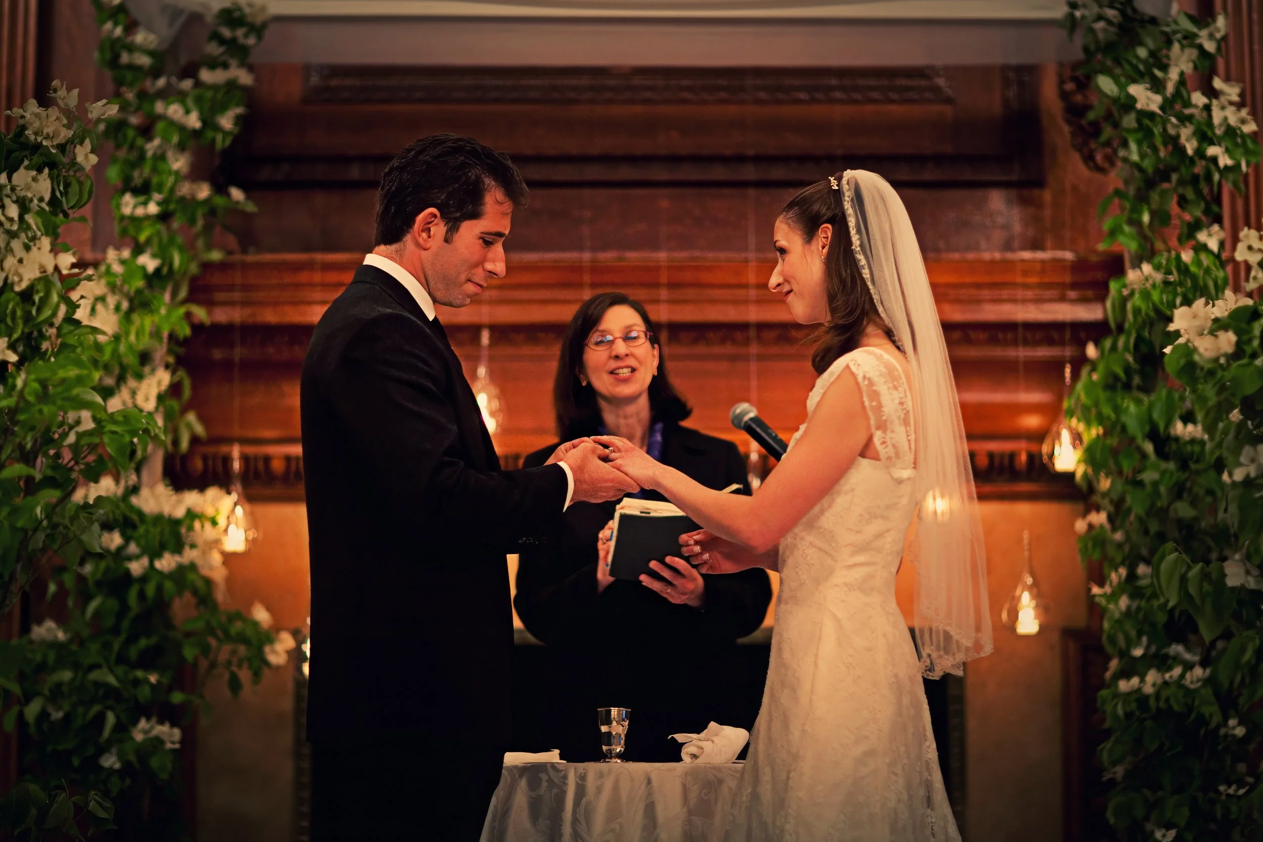 Bride and groom exchanging rings during a wedding ceremony in the ballroom at the Harmonie Club NYC