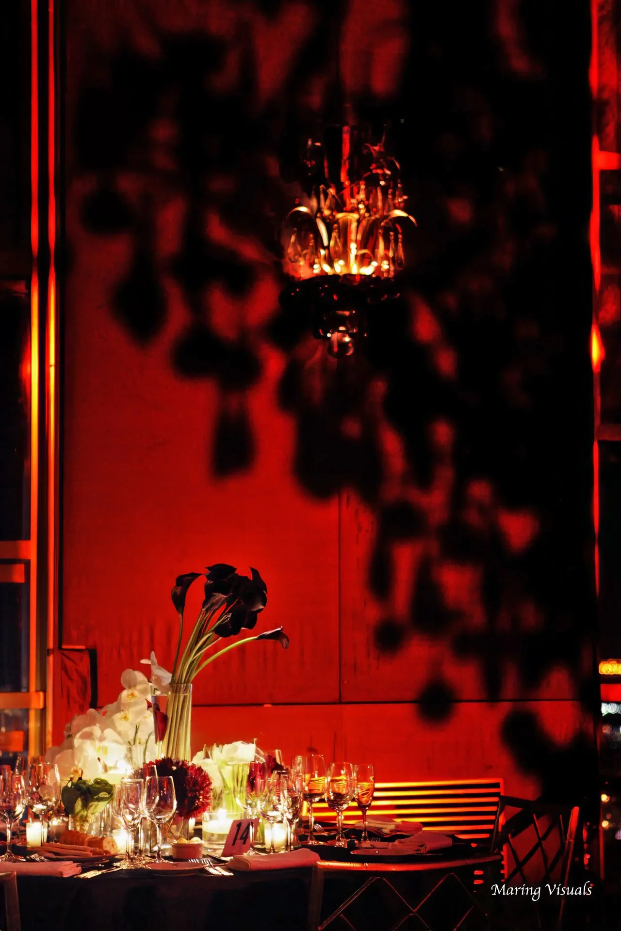 Chandelier light and elegant floral decor create dramatic shadows during a Rainbow Room wedding reception in New York City.