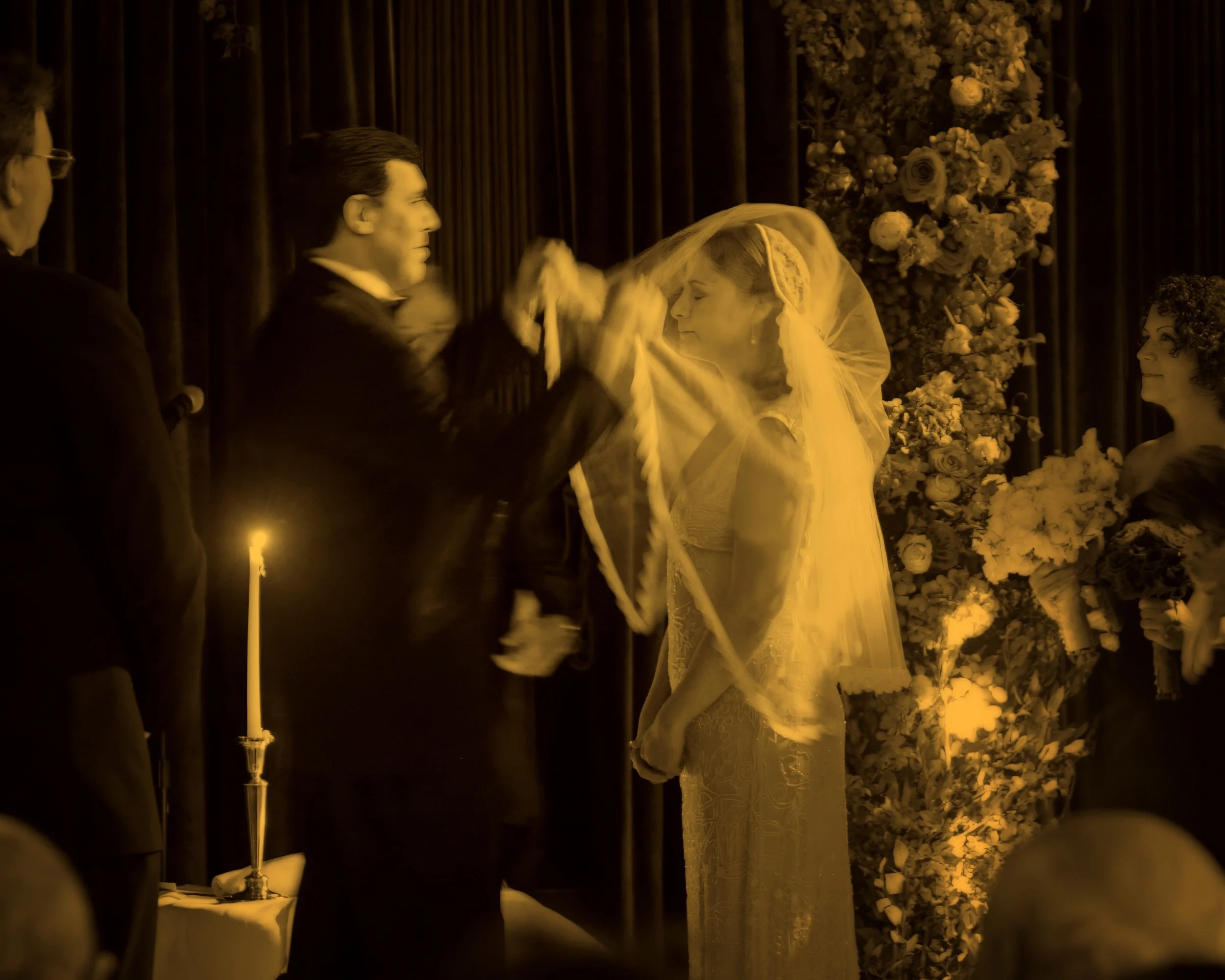 Fine art split-tone photo of the groom lifting the bride’s veil during a wedding ceremony at the Harvard Club NYC.