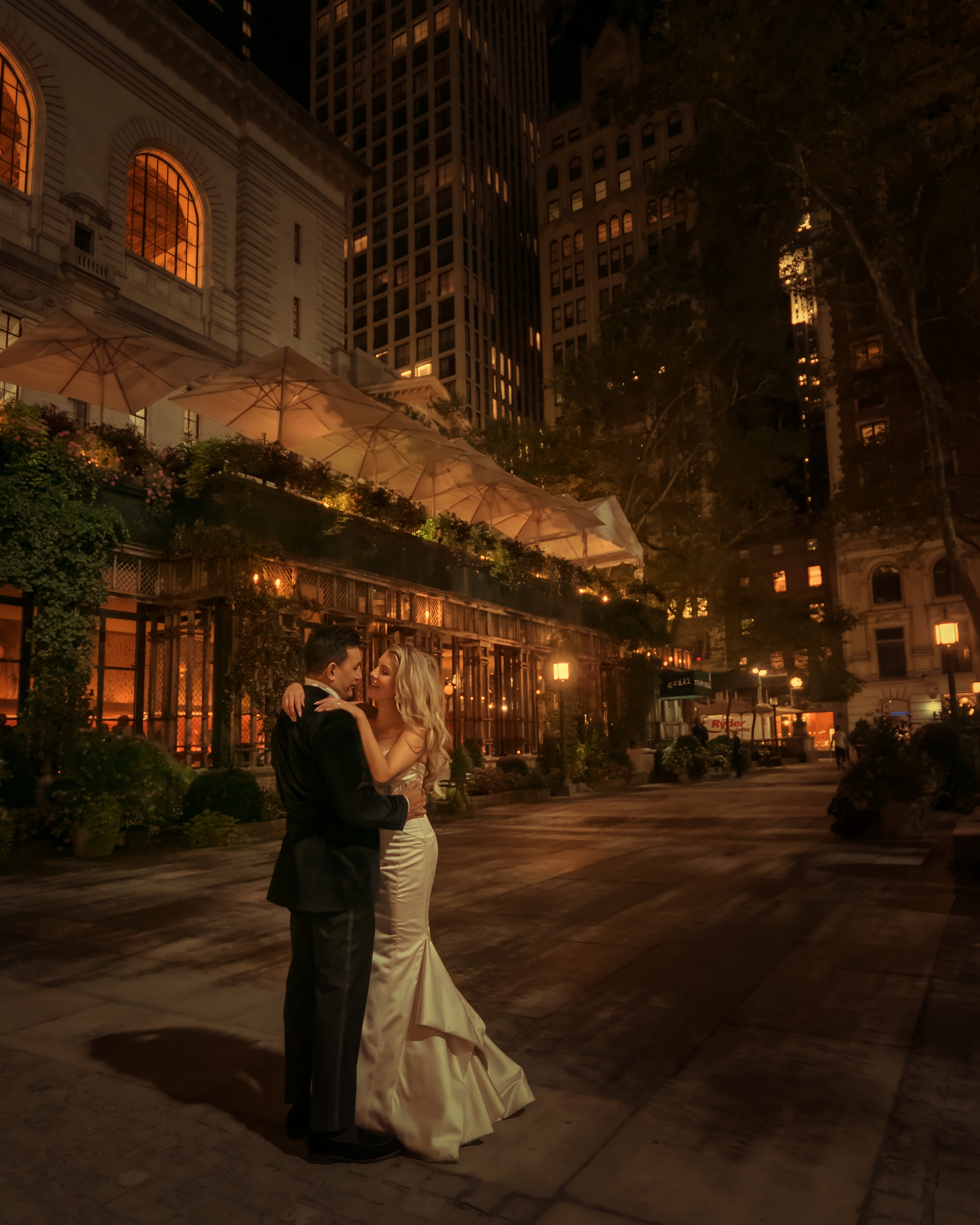 Bride and groom outside Bryant Park Grill at night with illuminated venue in Midtown Manhattan wedding