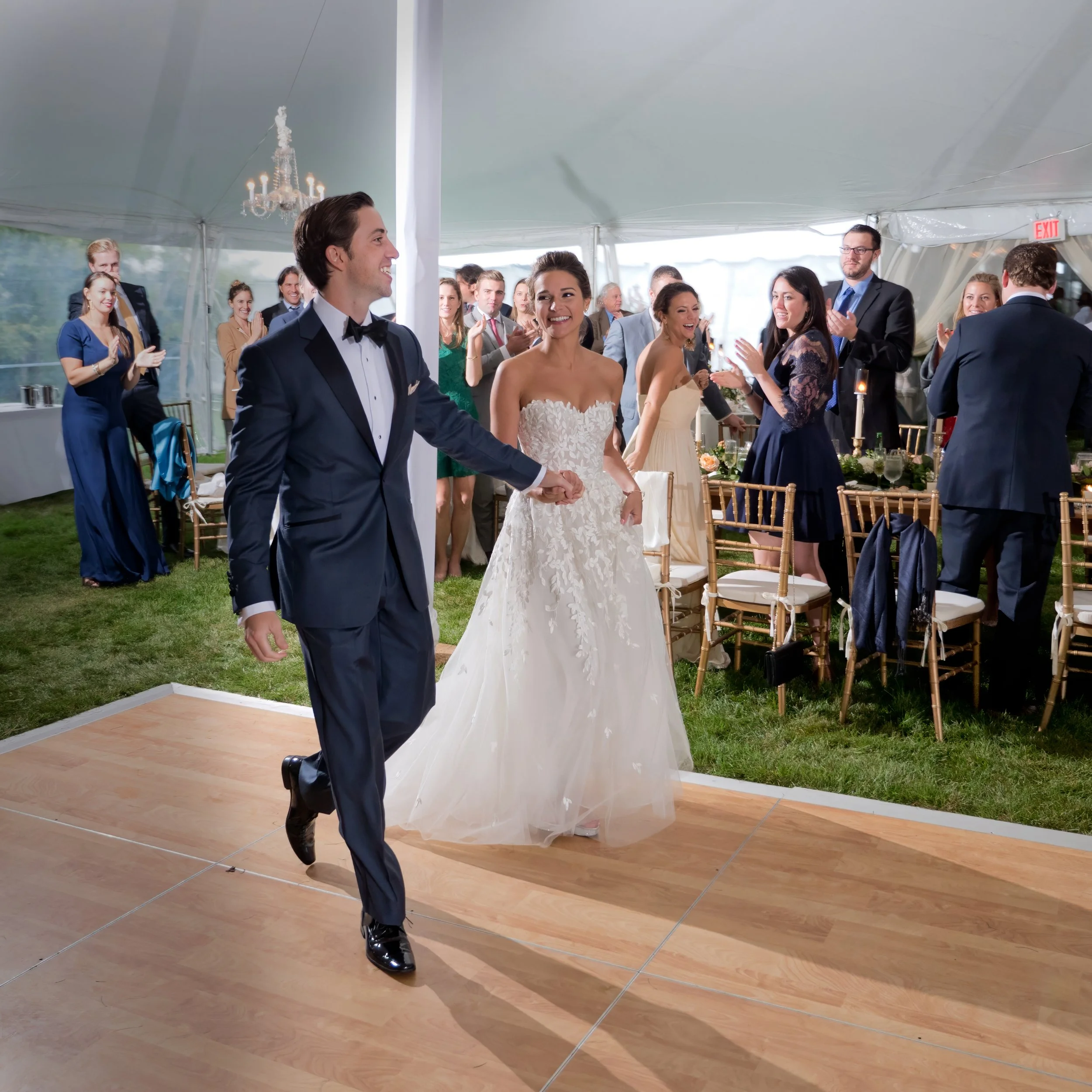 Bride and groom make a joyful grand entrance into their tented wedding reception at Lion Rock Farm surrounded by guests.