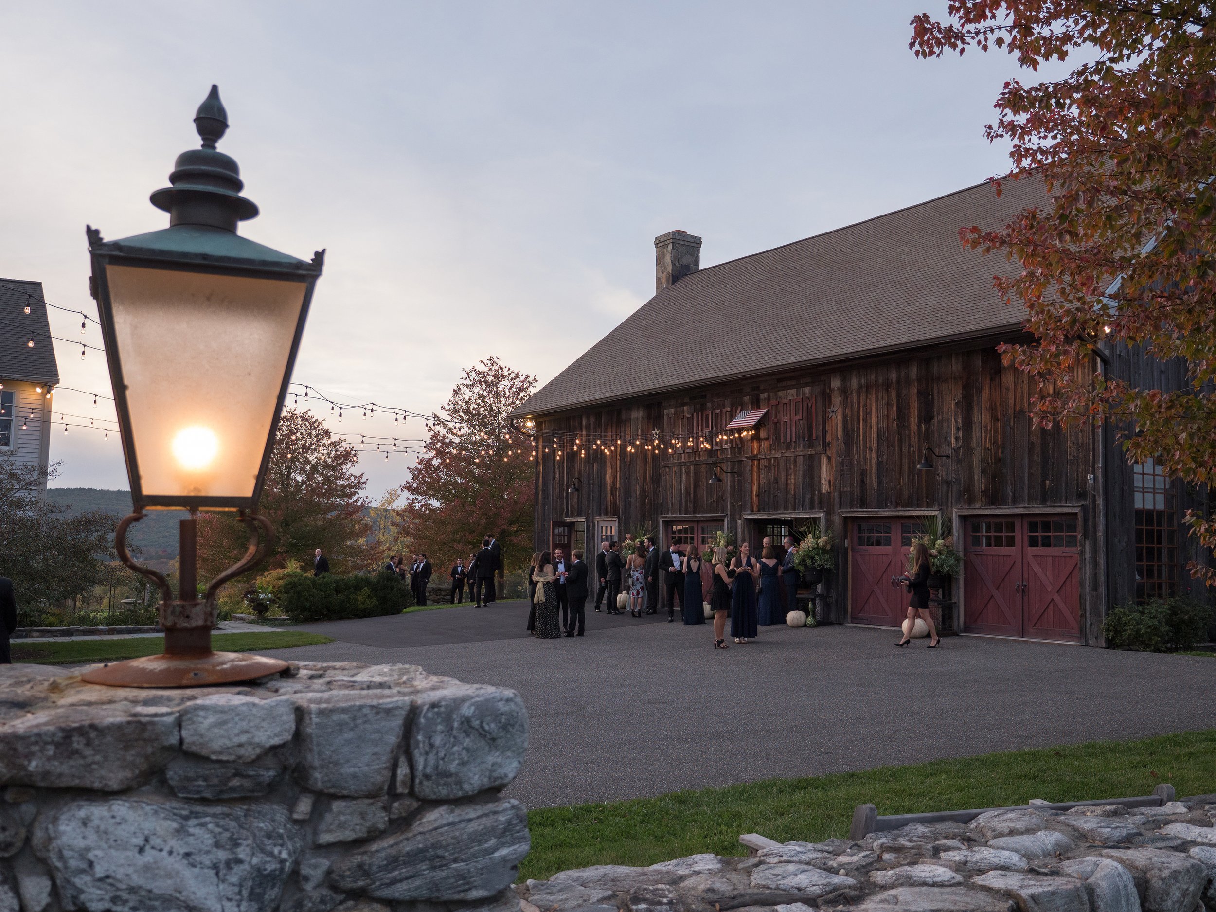 Wedding guests mingling outside barn during cocktail hour at Lion Rock Farm in Connecticut countryside