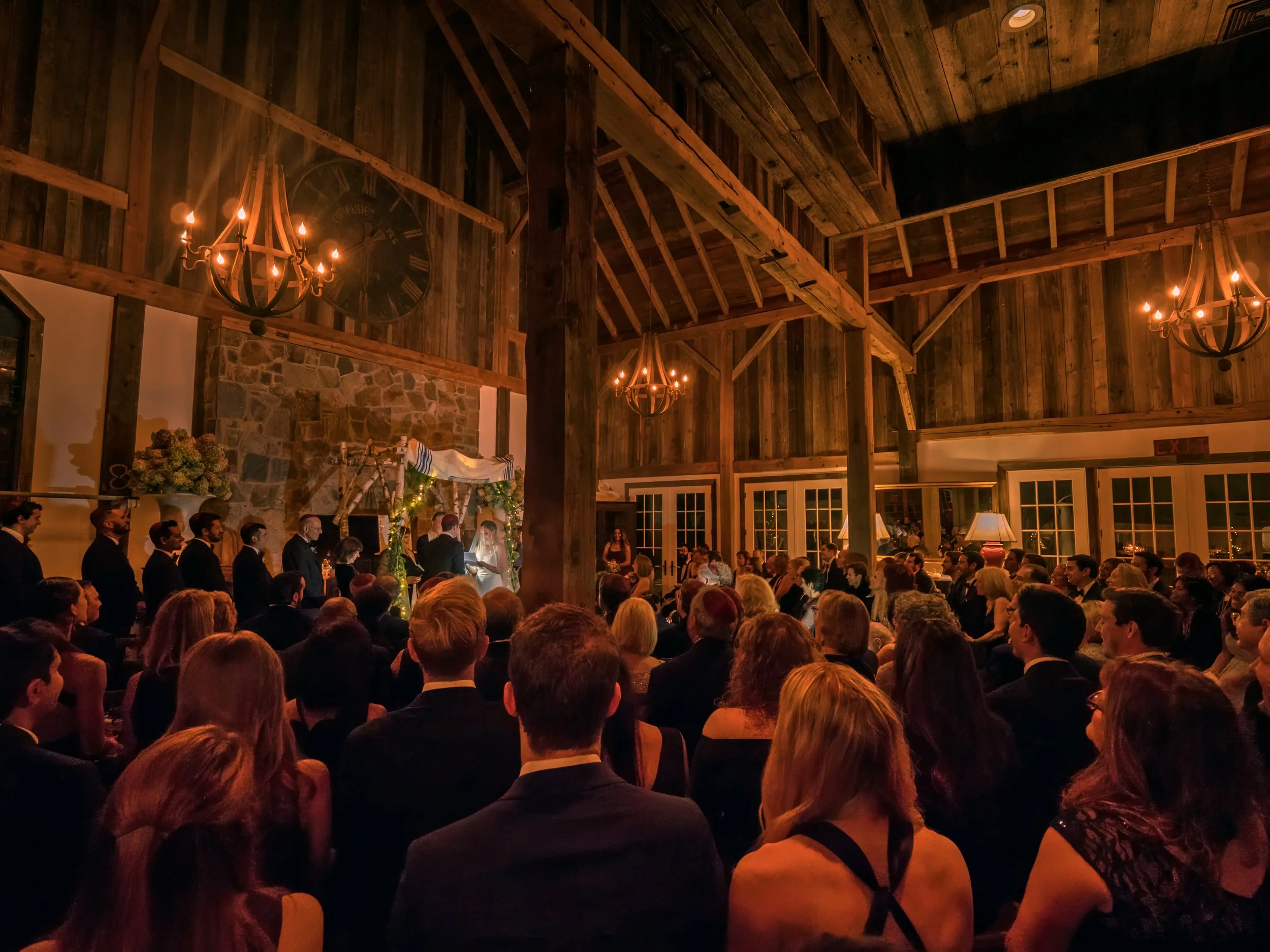 Bride and groom exchanging vows in barn ceremony at Lion Rock Farm with wide view of guests and space