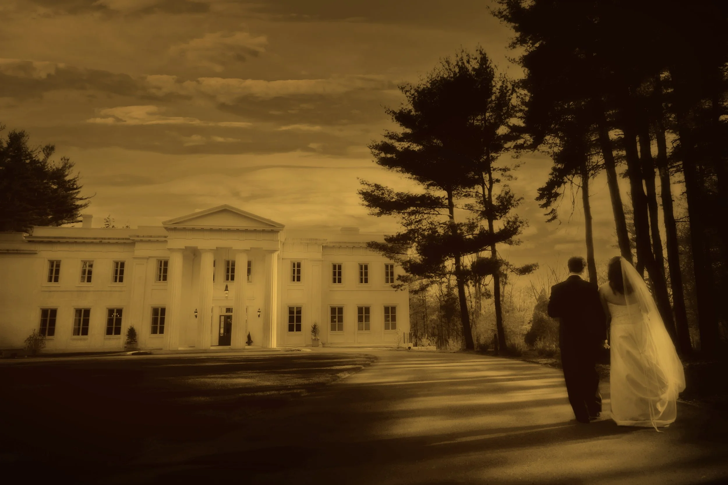 Bride and groom walk toward the front facade of Wadsworth Mansion in ethereal split tone fine art wedding photograph