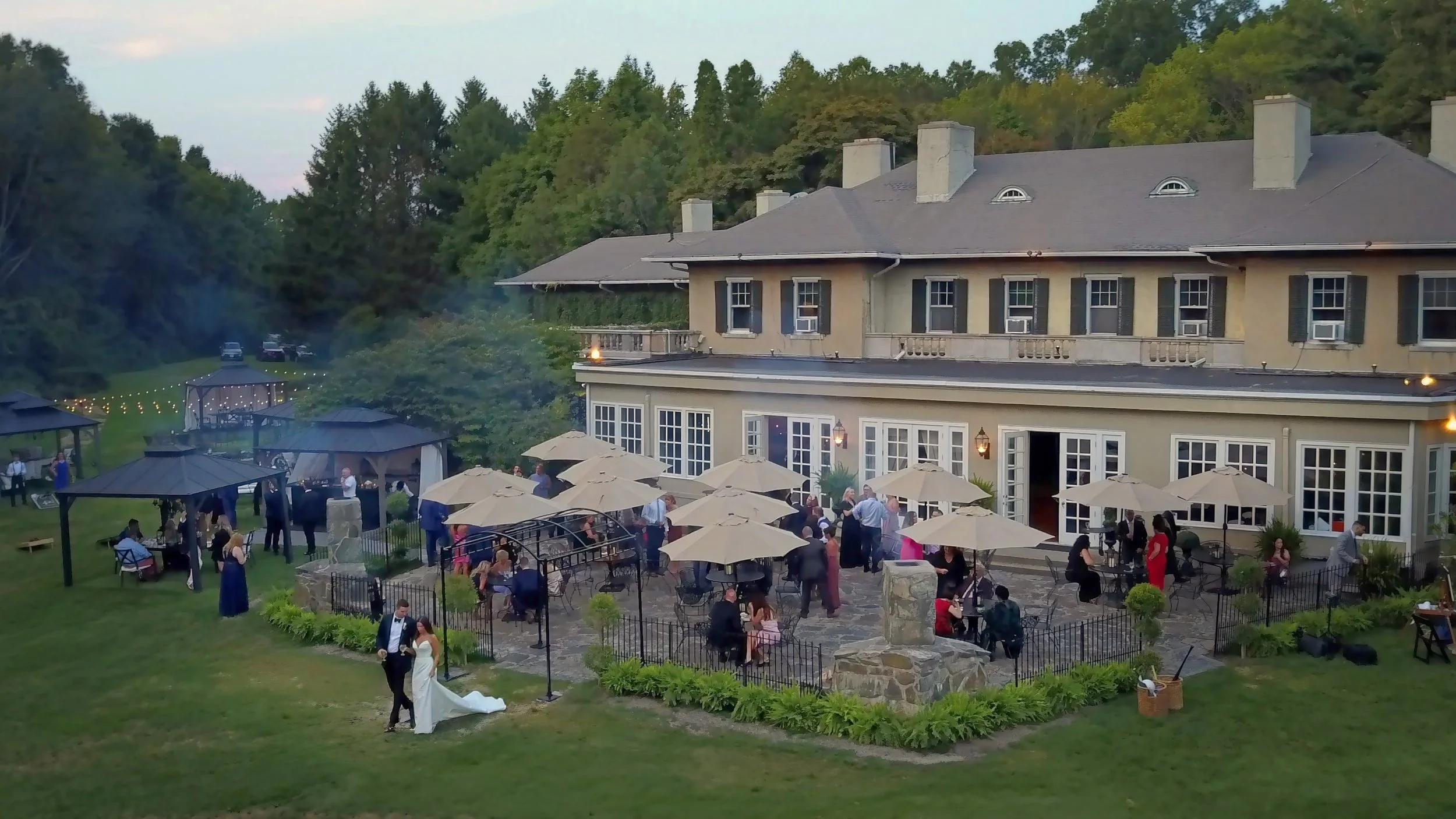 Wedding cocktail hour guests mingling as couple walks at Lord Thompson Manor