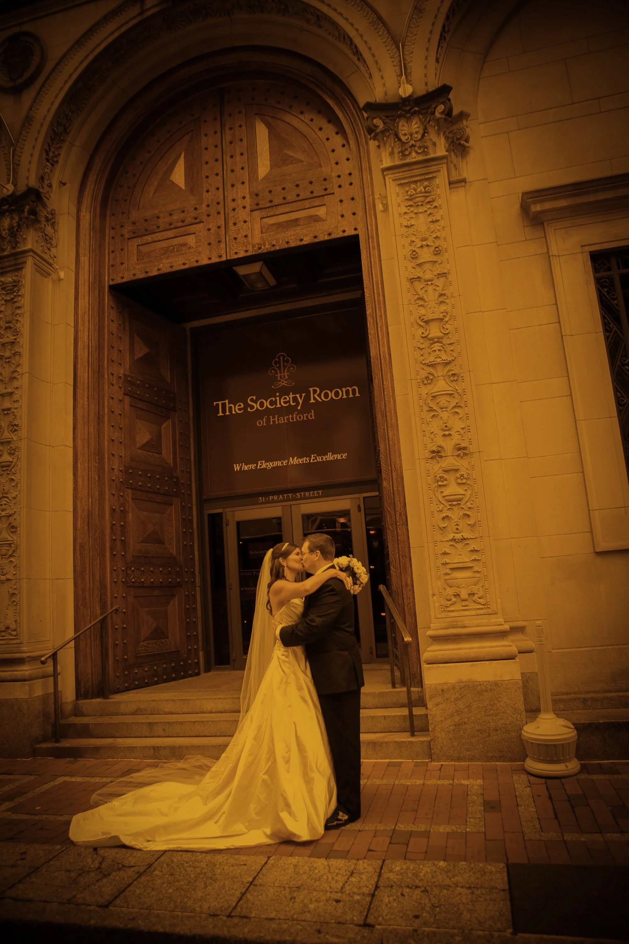 Bride and groom kissing at entrance of The Society Room of Hartford wedding venue