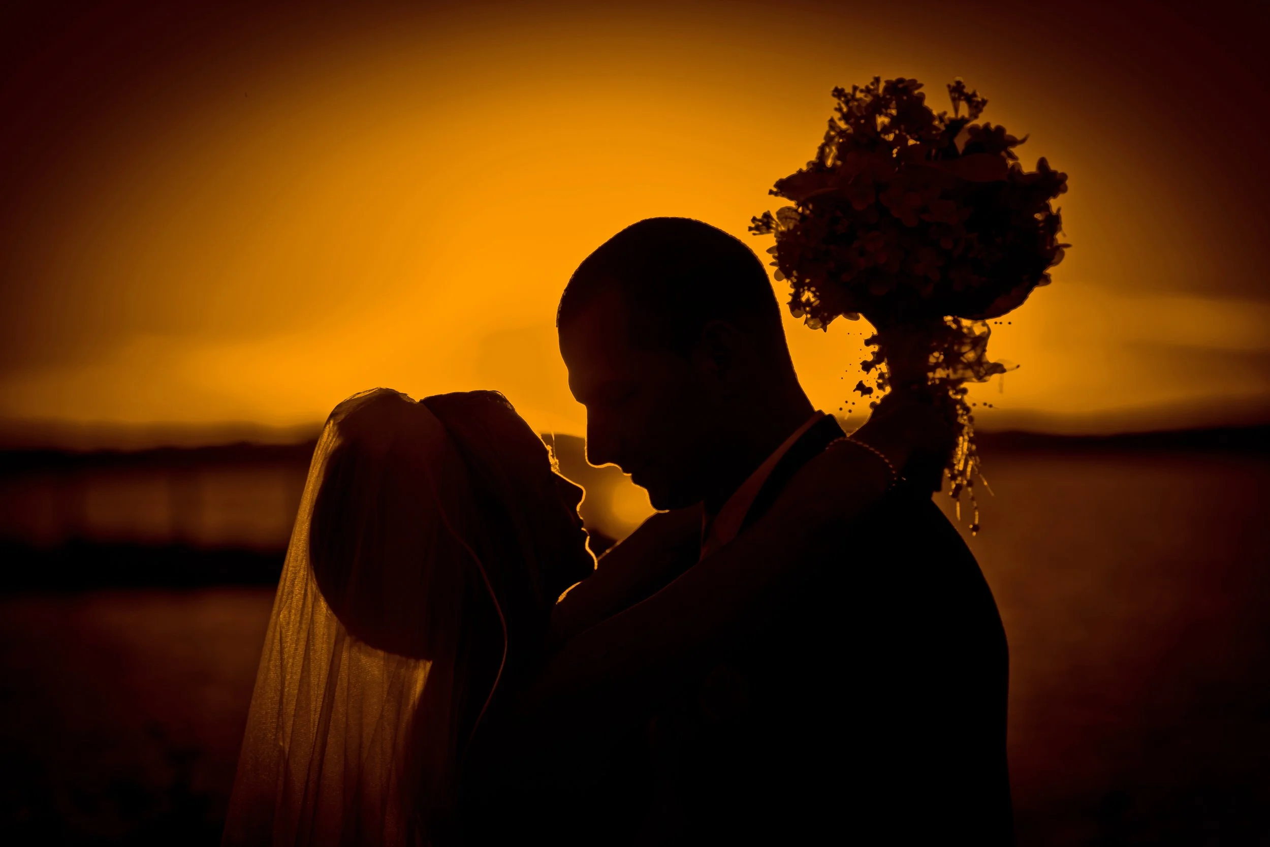 Silhouette portrait of bride and groom with New Haven Harbor in the distance at Amarante’s Sea Cliff