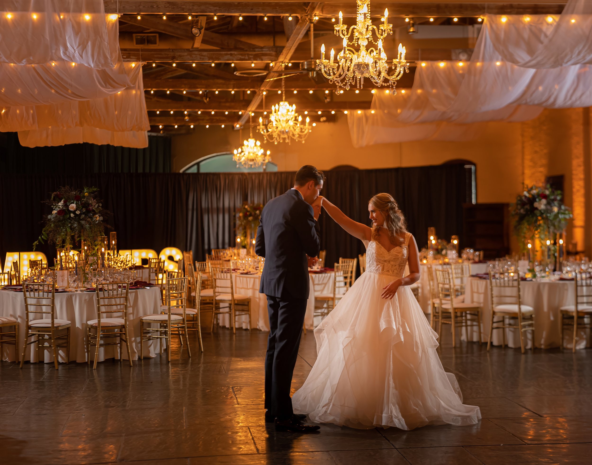Groom Kissing Bride’s Hand During Ballroom Reveal at Savannah Station