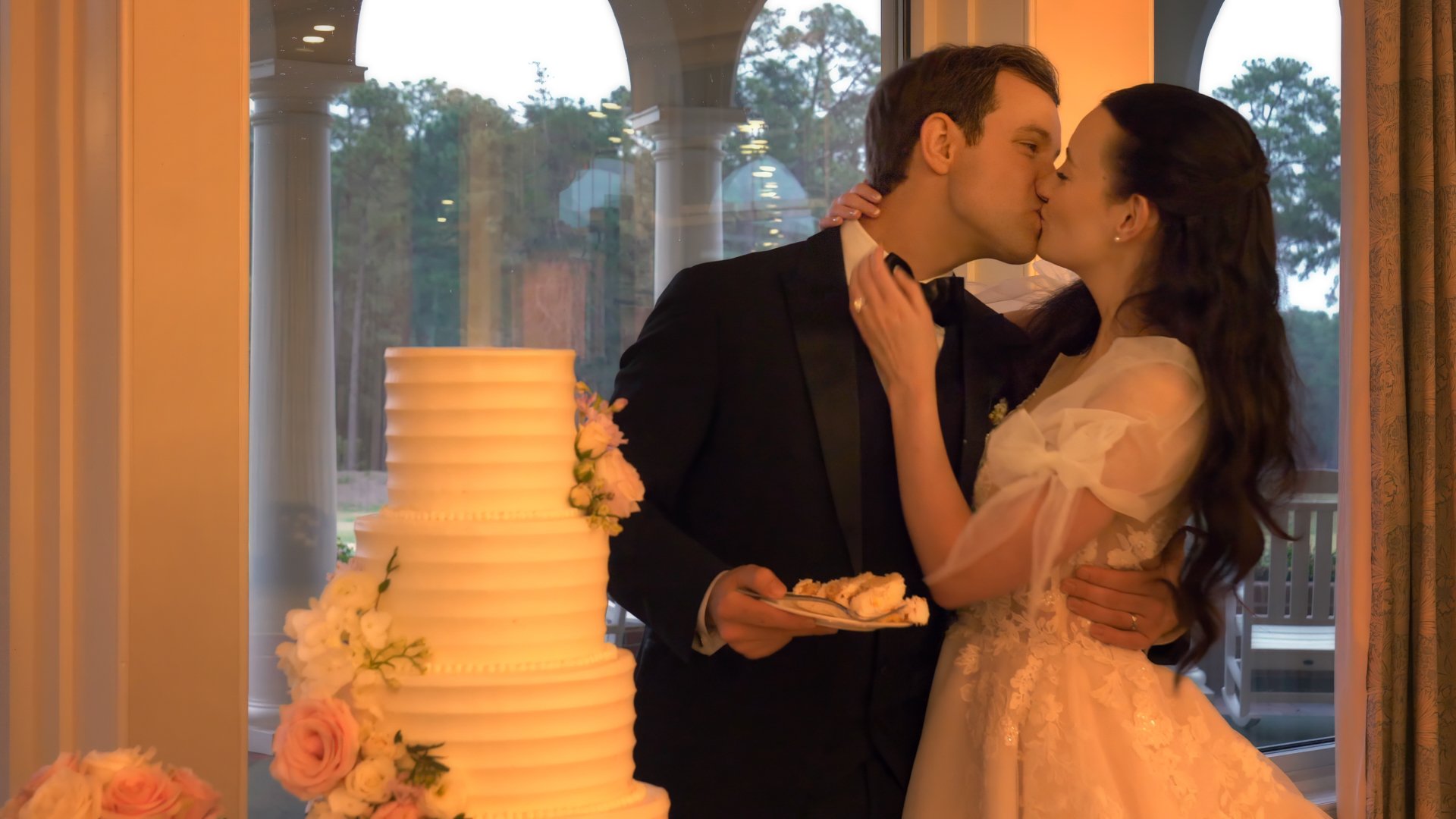 Bride and groom kiss after cutting wedding cake at Pinehurst Resort Clubhouse reception