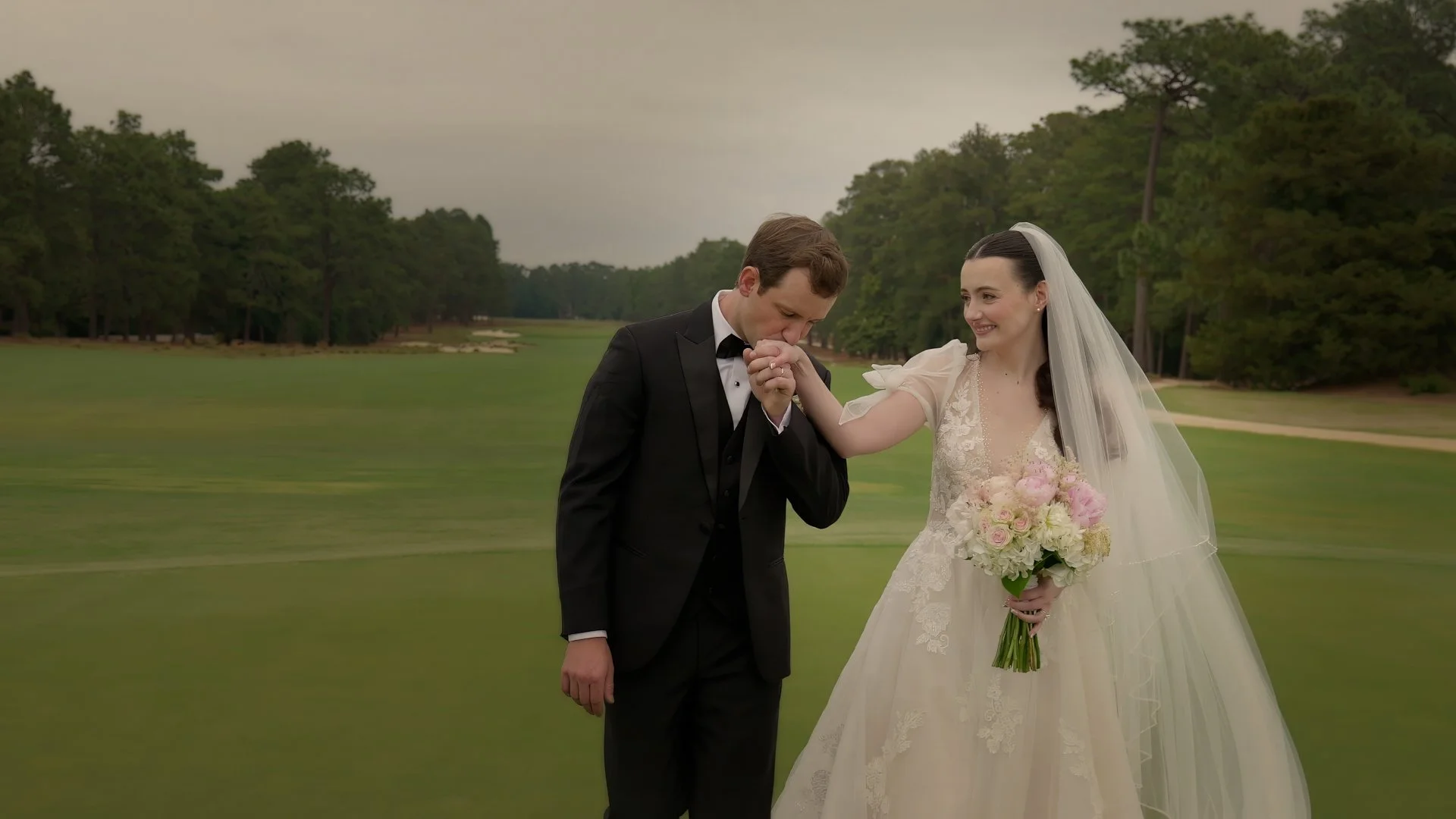 Groom kissing bride’s hand candid moment on Pinehurst Resort golf course wedding portrait