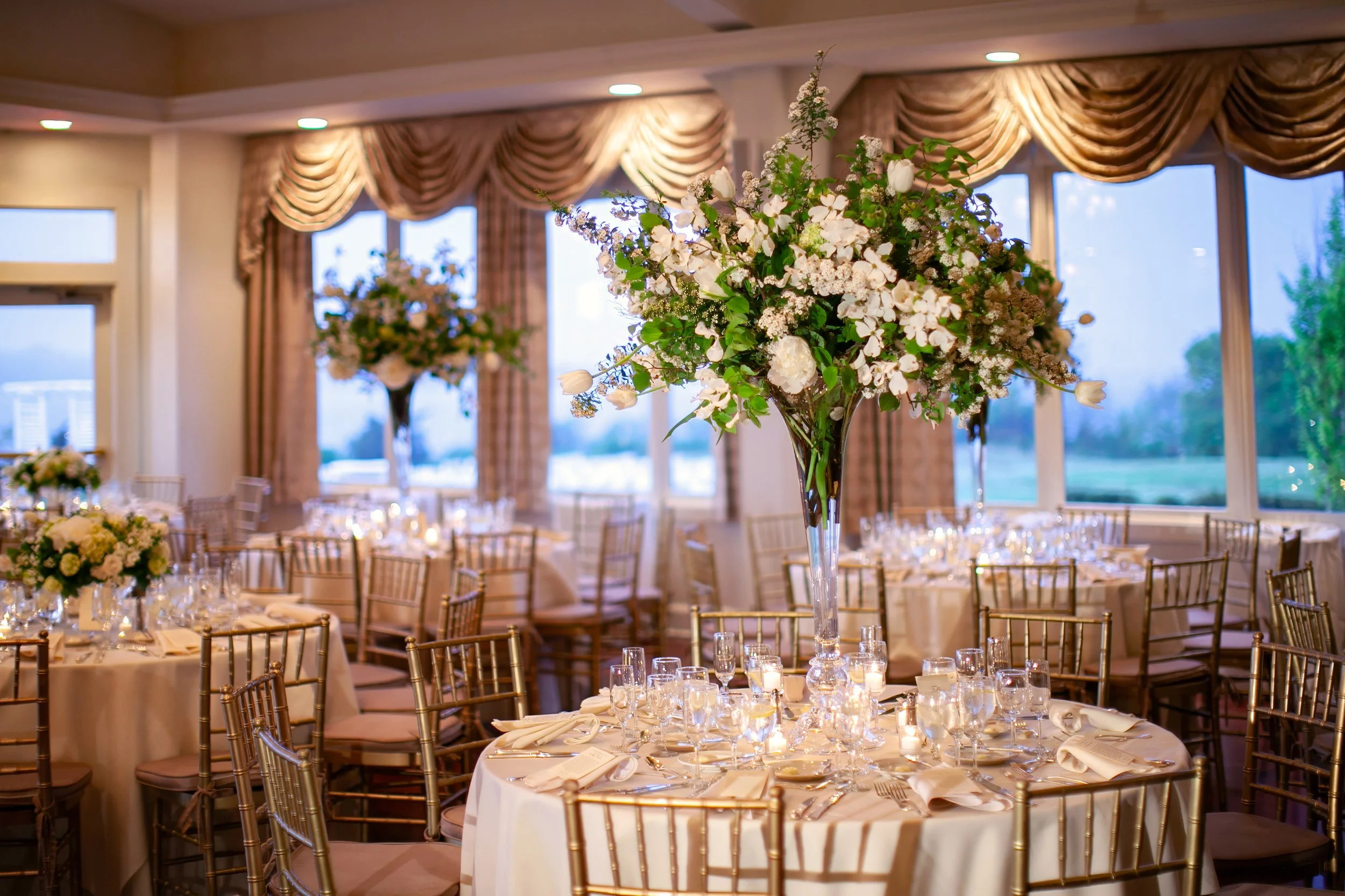 Ballroom wedding reception decor at Ocean Cliff with chandeliers and elegant table settings.