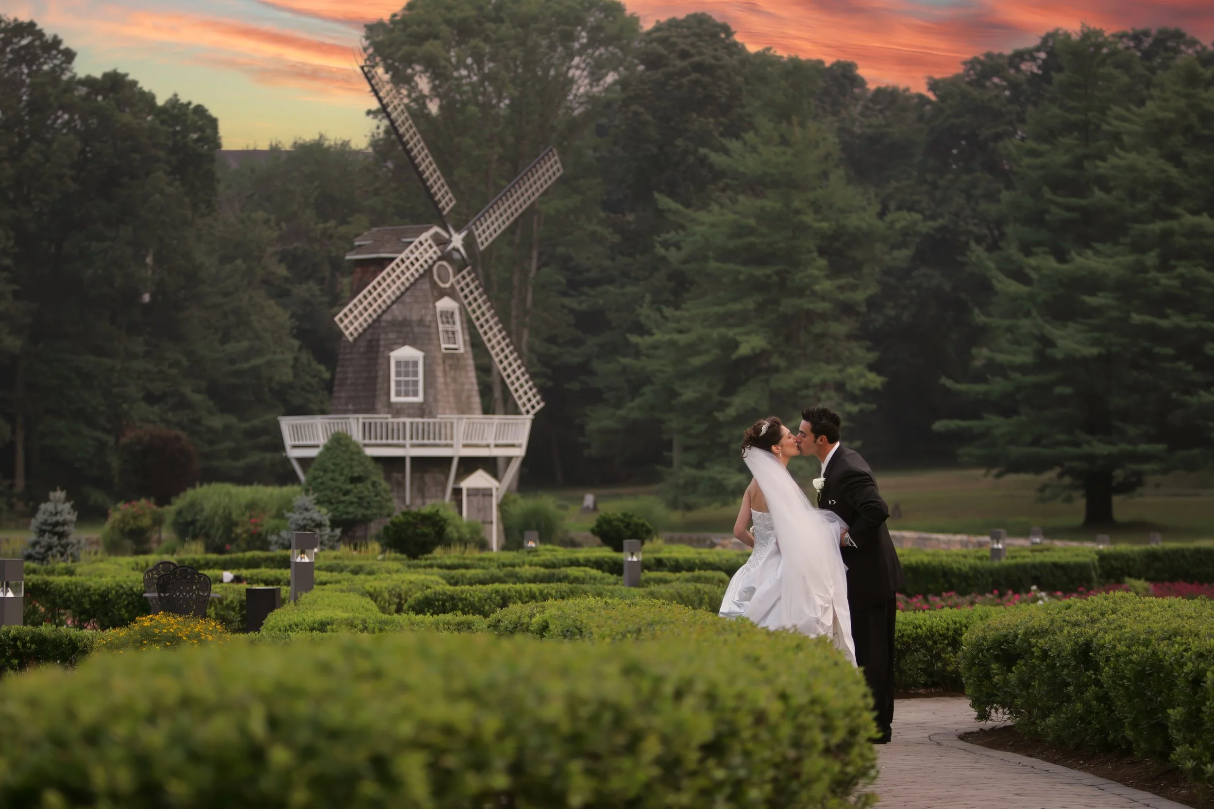Bride and groom kiss on the grounds of Aqua Turf with a windmill in the distance