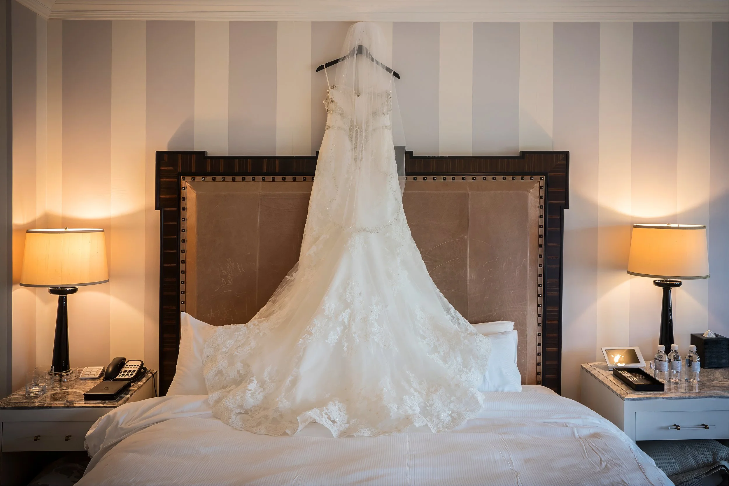 Wedding dress hanging above the bed in a luxury suite at Lotte New York Palace Hotel