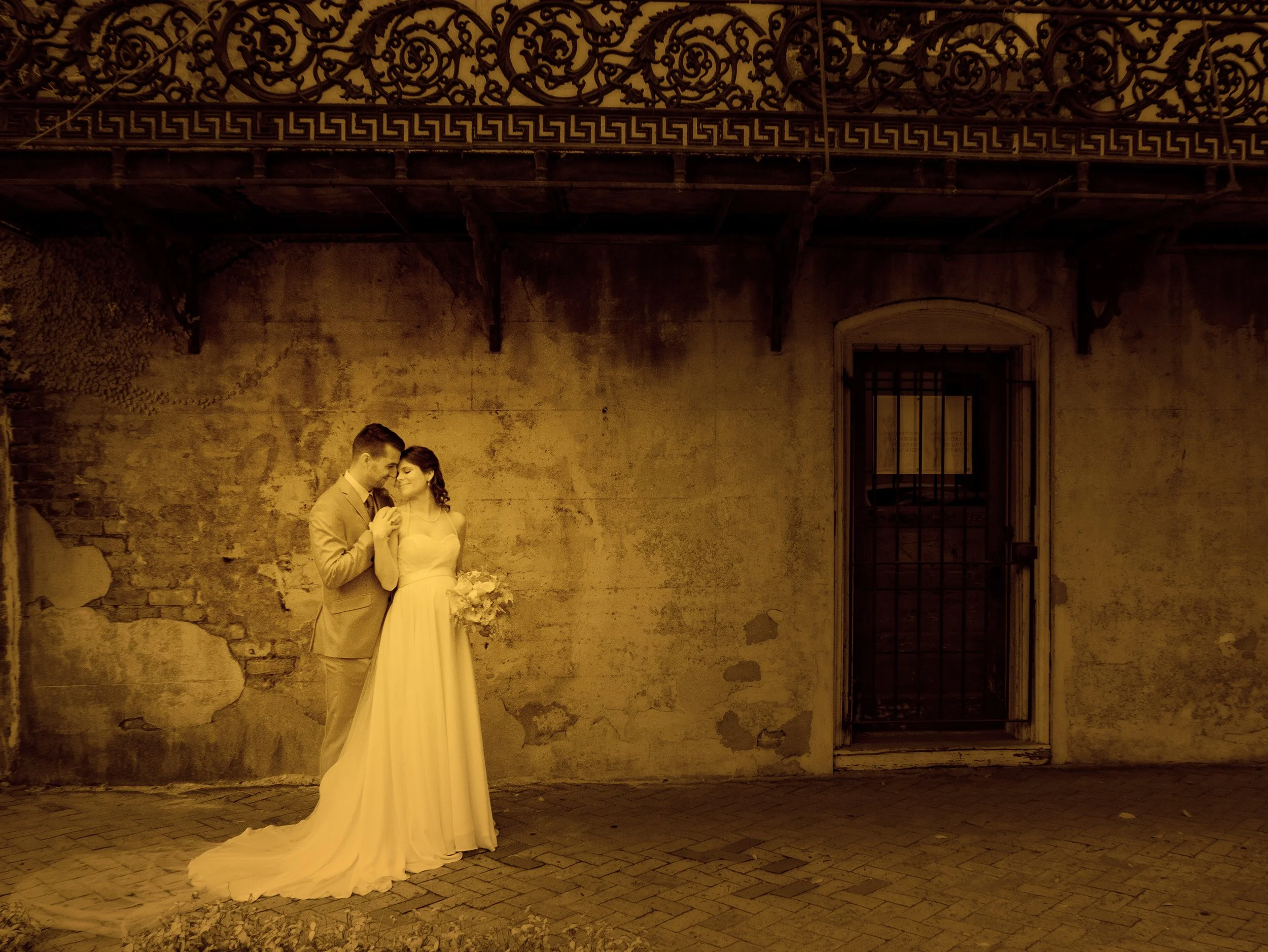 Poetic fine art split toned portrait of bride and groom against historic mansion walls on Bull Street near Forsyth Park, Savannah.
