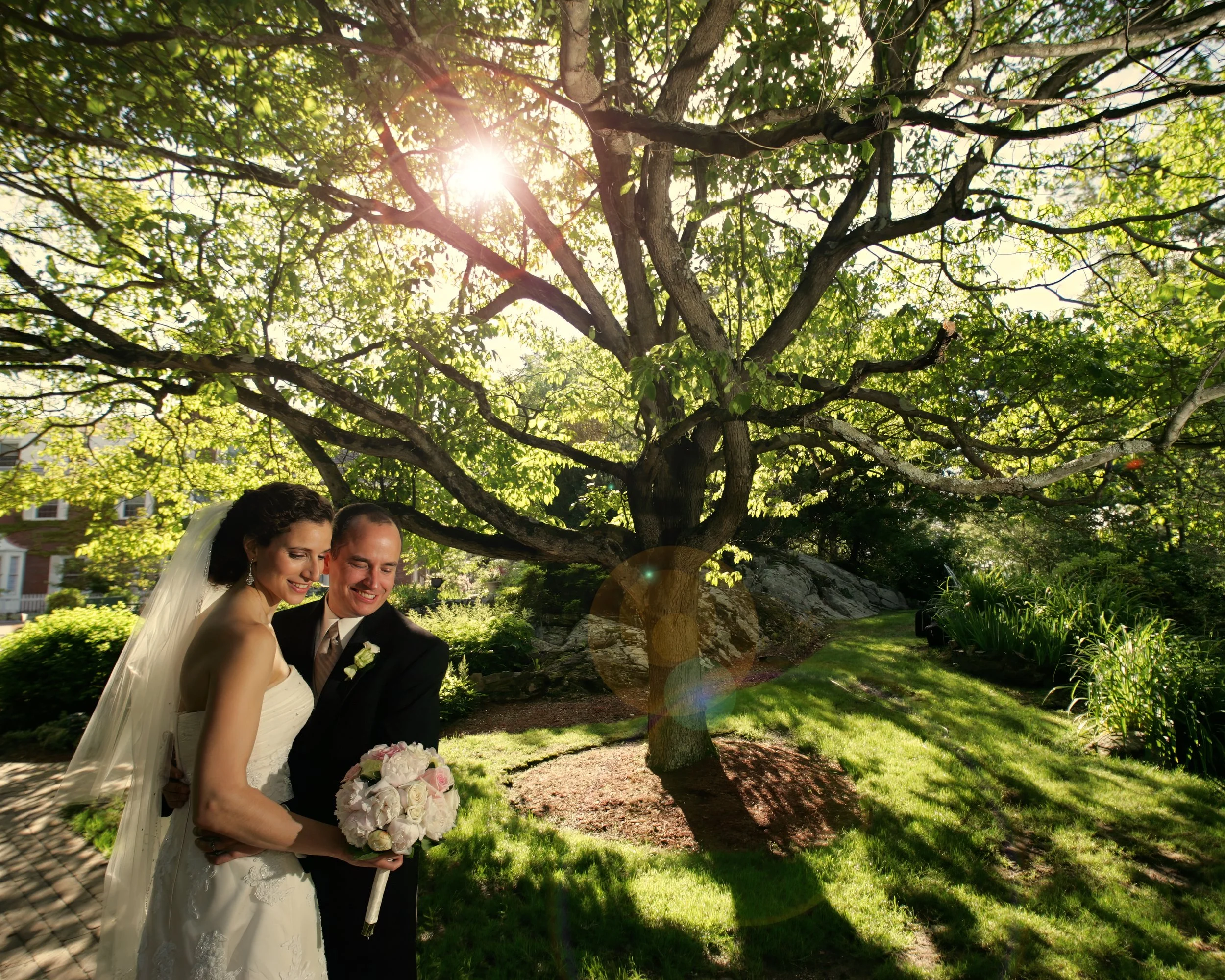 Sunlit bride and groom portraits on the grounds of the Spa at Norwich Inn with gardens in the background.