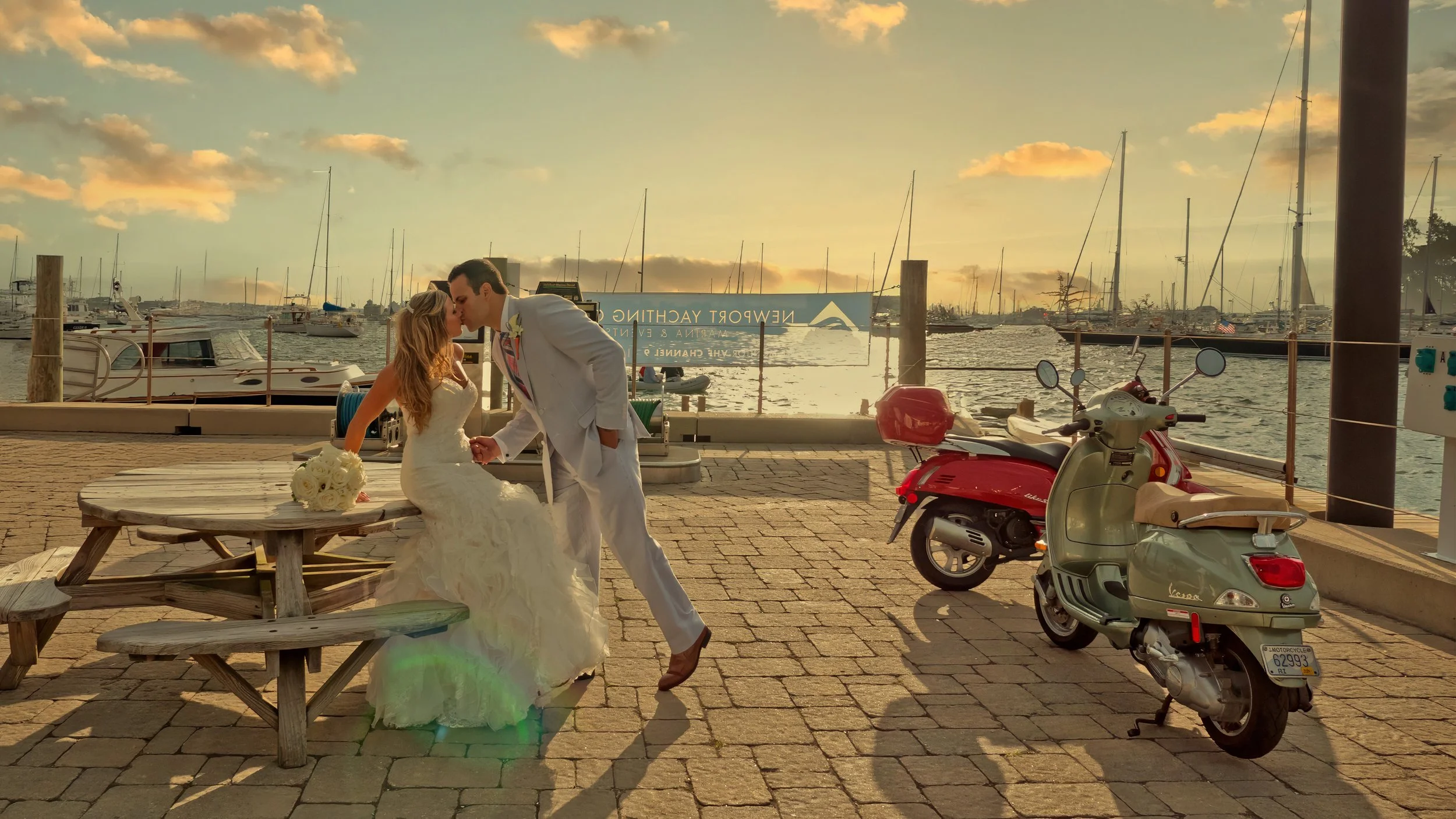 Bride and groom share a kiss on the docks of the Newport Yachting Center in the warm late day sunlight.