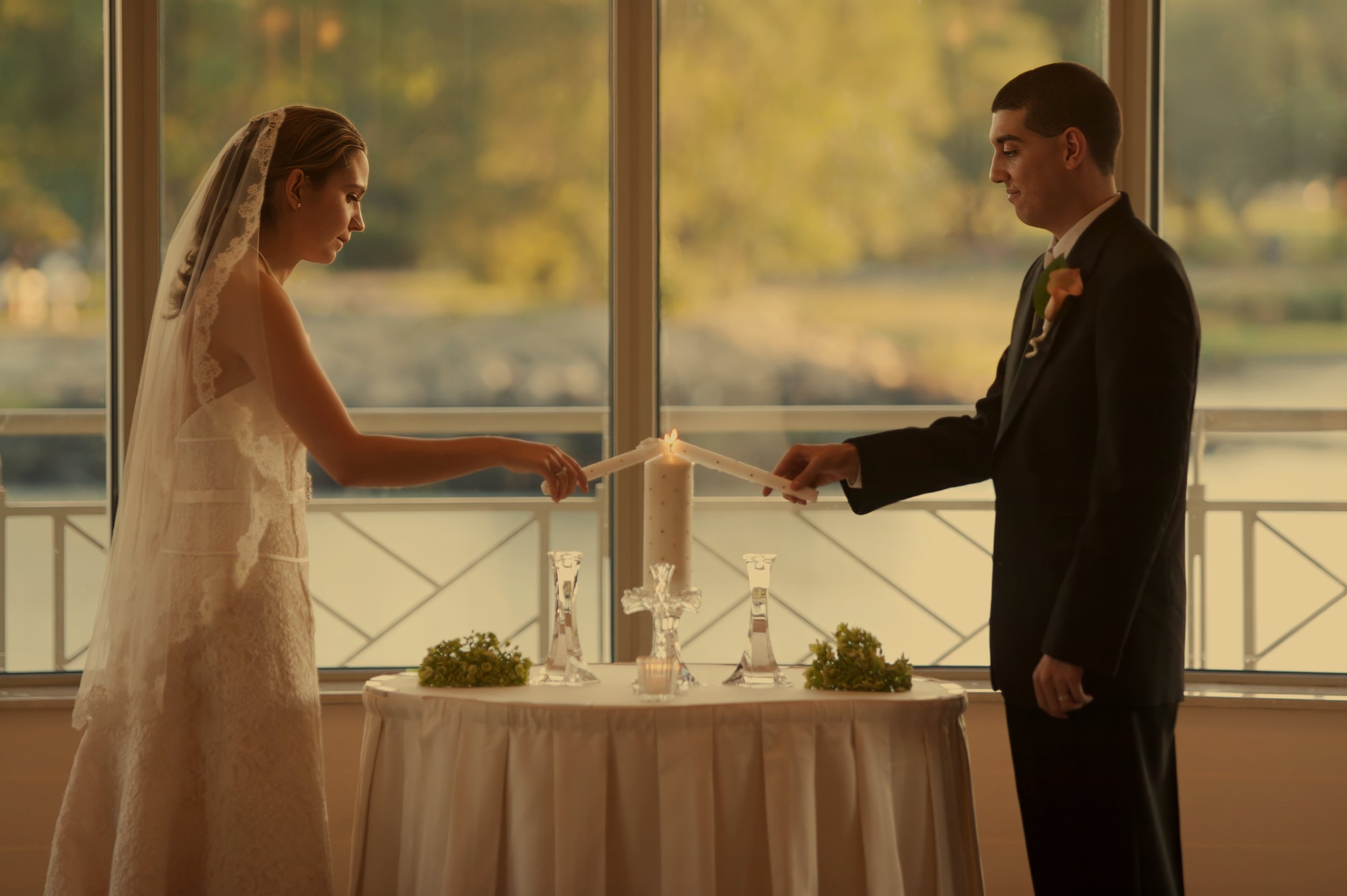 Bride and groom light their wedding candle at an indoor ceremony at Glen Island Harbour Club