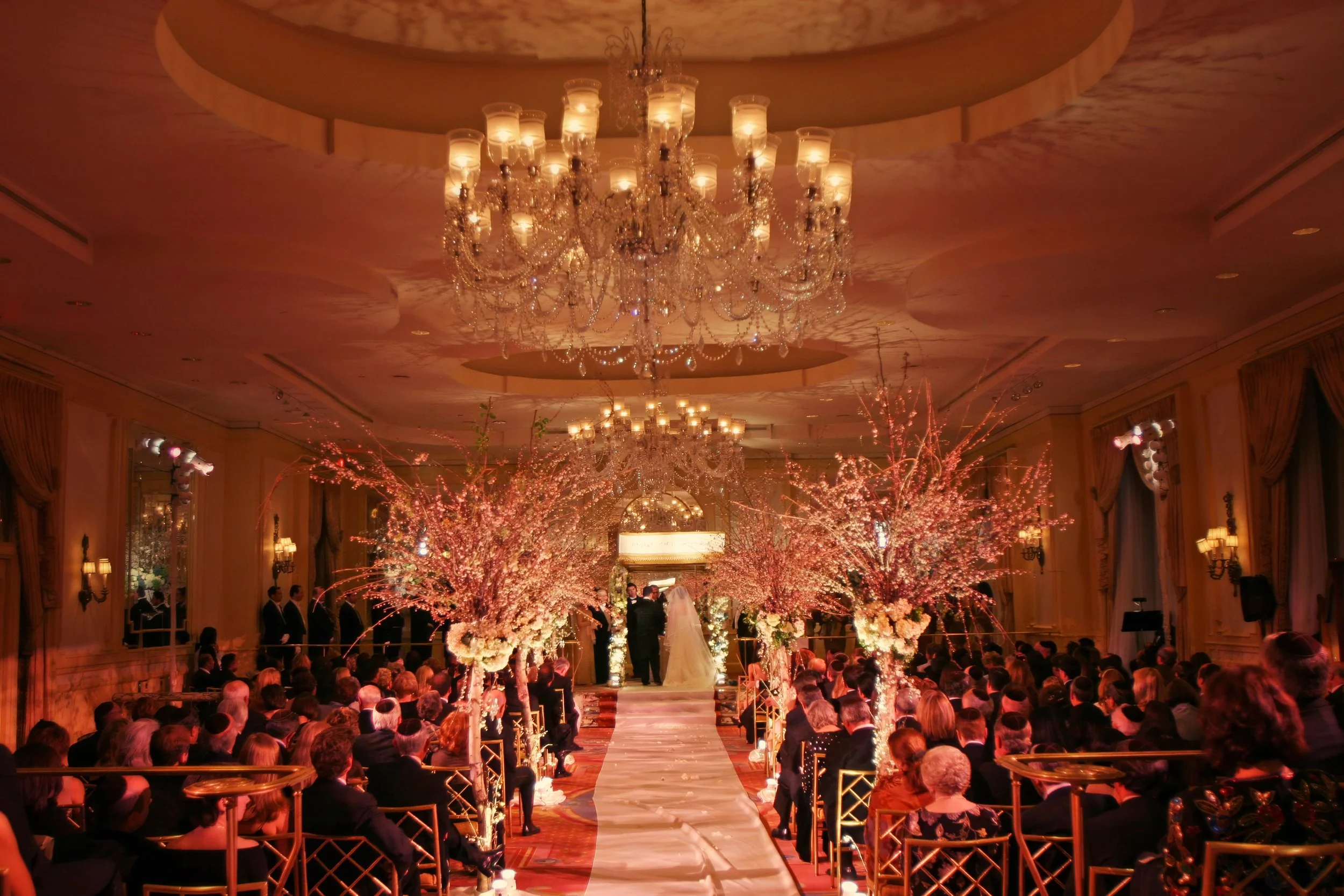 Sweeping view of a lavishly decorated  wedding ceremony in the Cotillion Ballroom at The Pierre Hotel NYC with elegant floral and seating