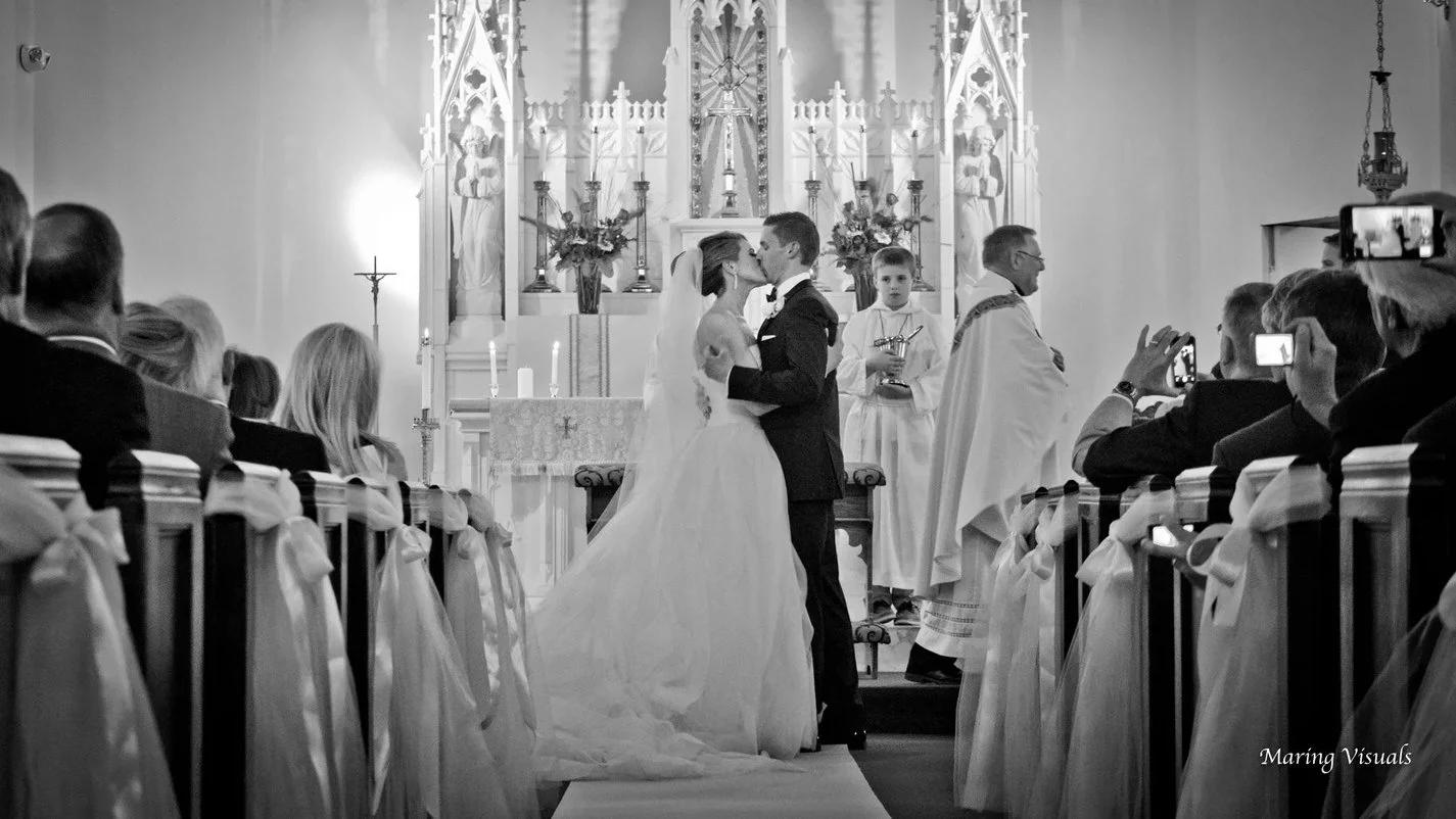Bride and groom share a kiss at the altar during their cathedral wedding ceremony in Westchester, New York, photographed in fine art black and white.