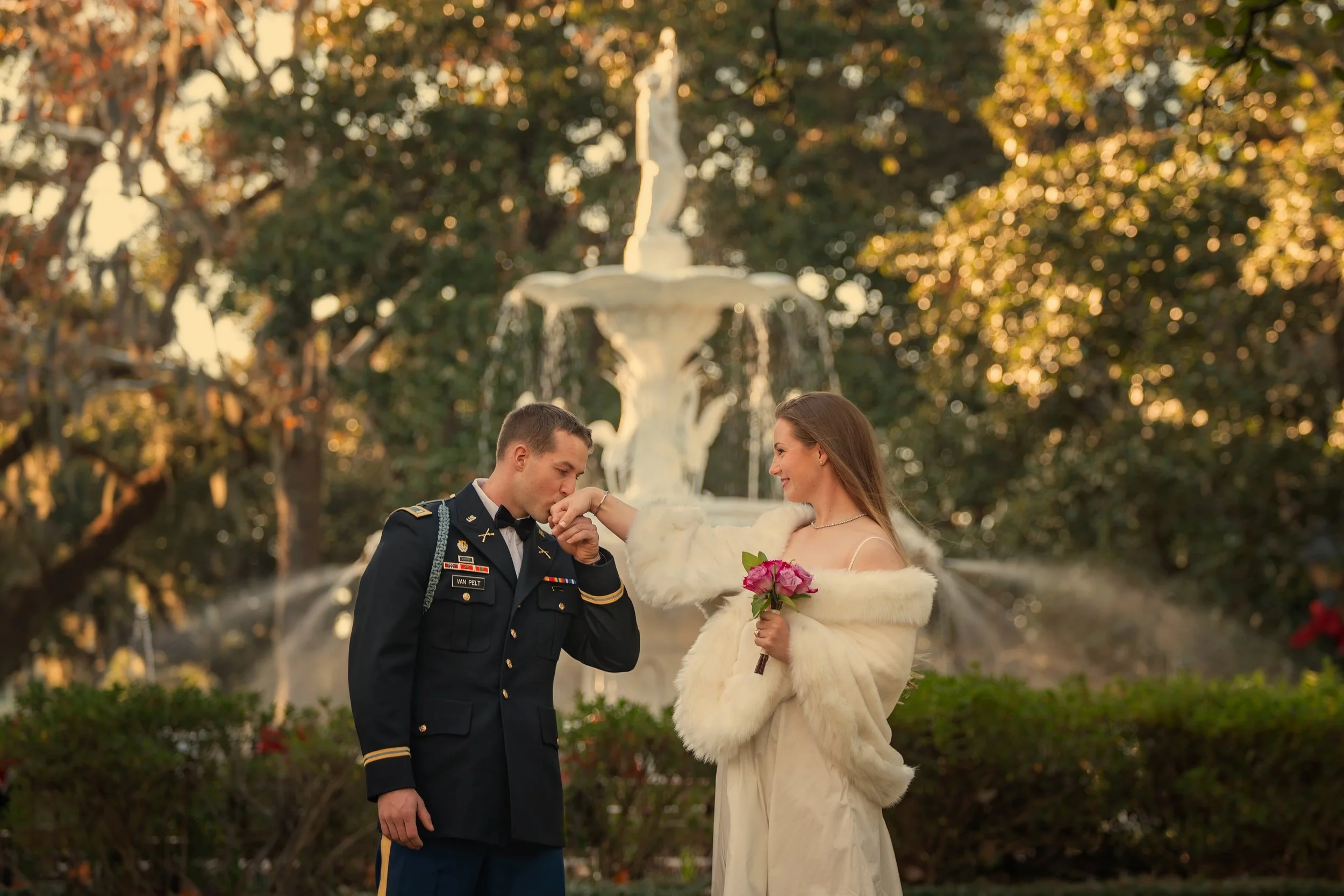 Groom kisses bride’s hand in front of the Forsyth Park fountain during an intimate Savannah elopement at Forsyth Park in Savannah, Georgia.