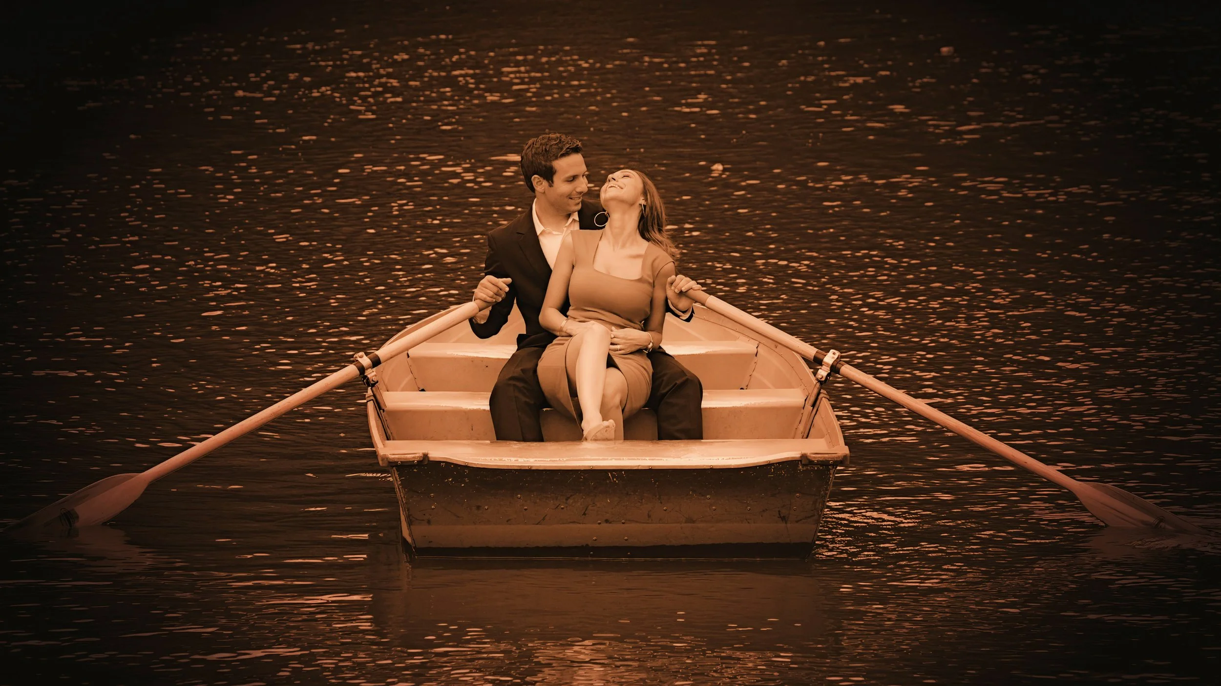 Romantic engagement portrait of a couple in a rowboat on Central Park Lake captured from a distance