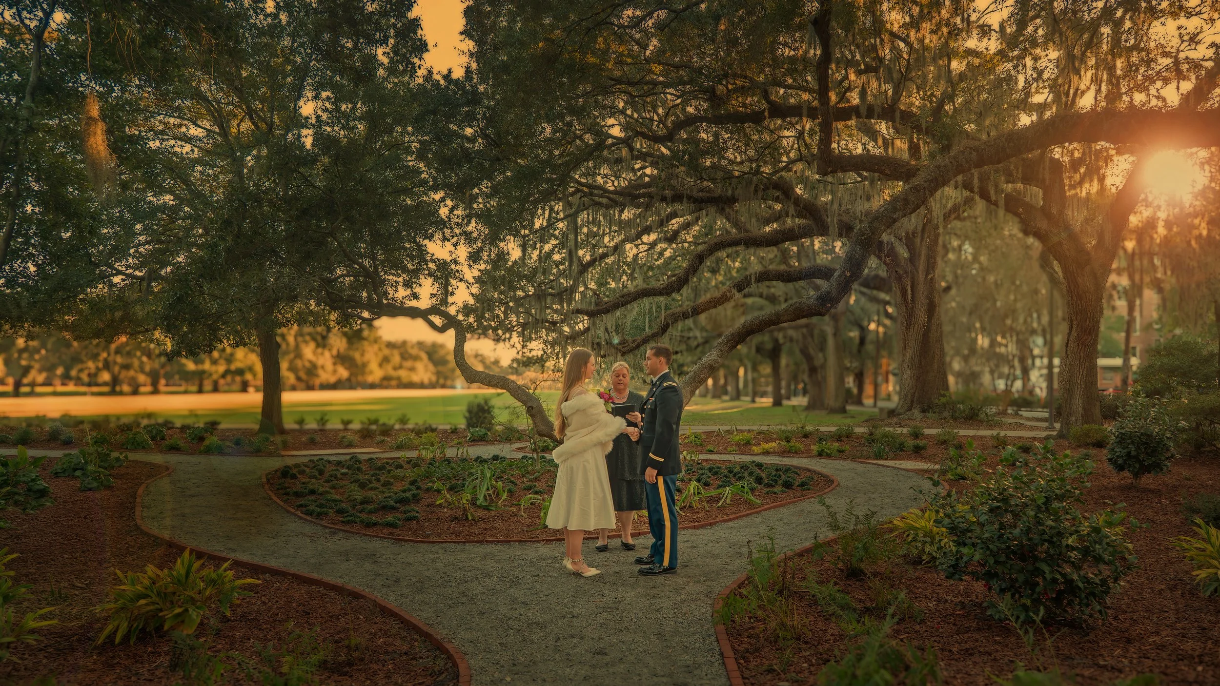 Bride and groom exchange vows during an intimate wedding ceremony at Forsyth Park in Savannah with warm sun flares through the trees.