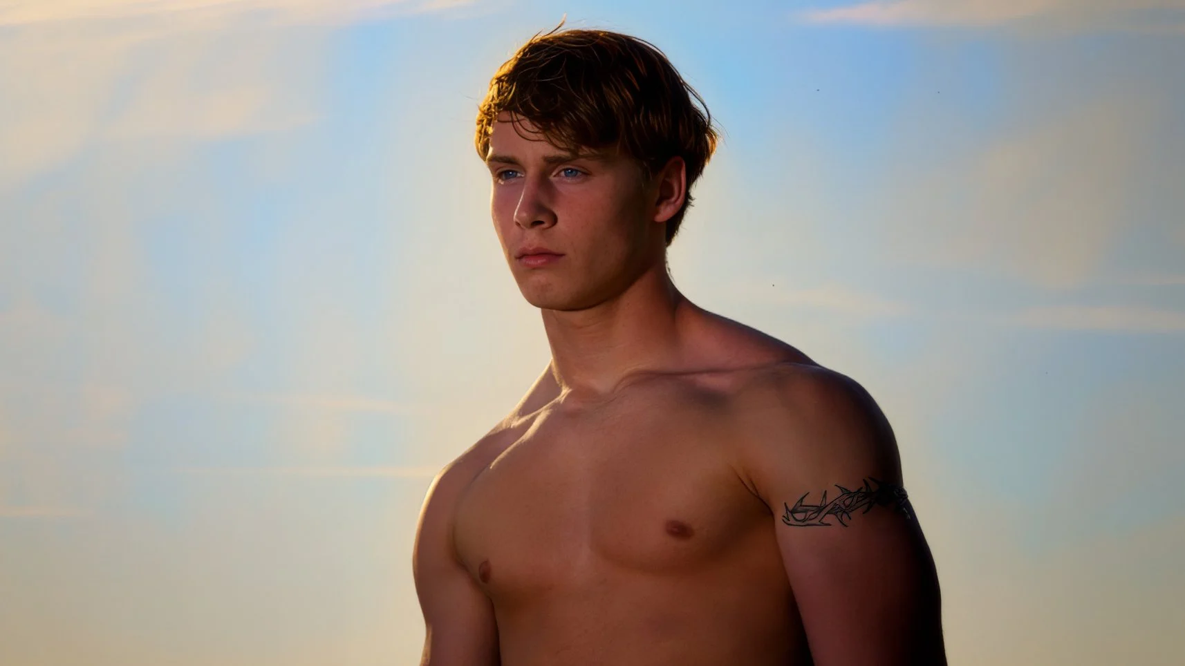 All-American young male posing shirtless against blue sky in fashion photography session