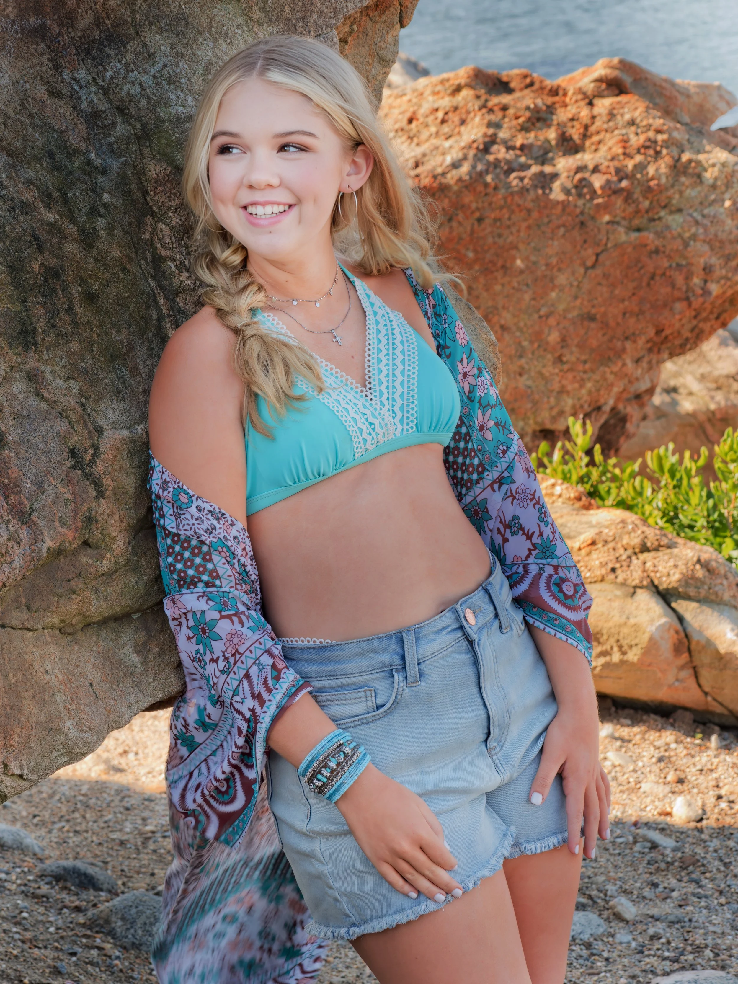 Senior portrait of a student on the sandy beach at Hammonasset State Park in Connecticut, rocks and Long Island Sound in the background.