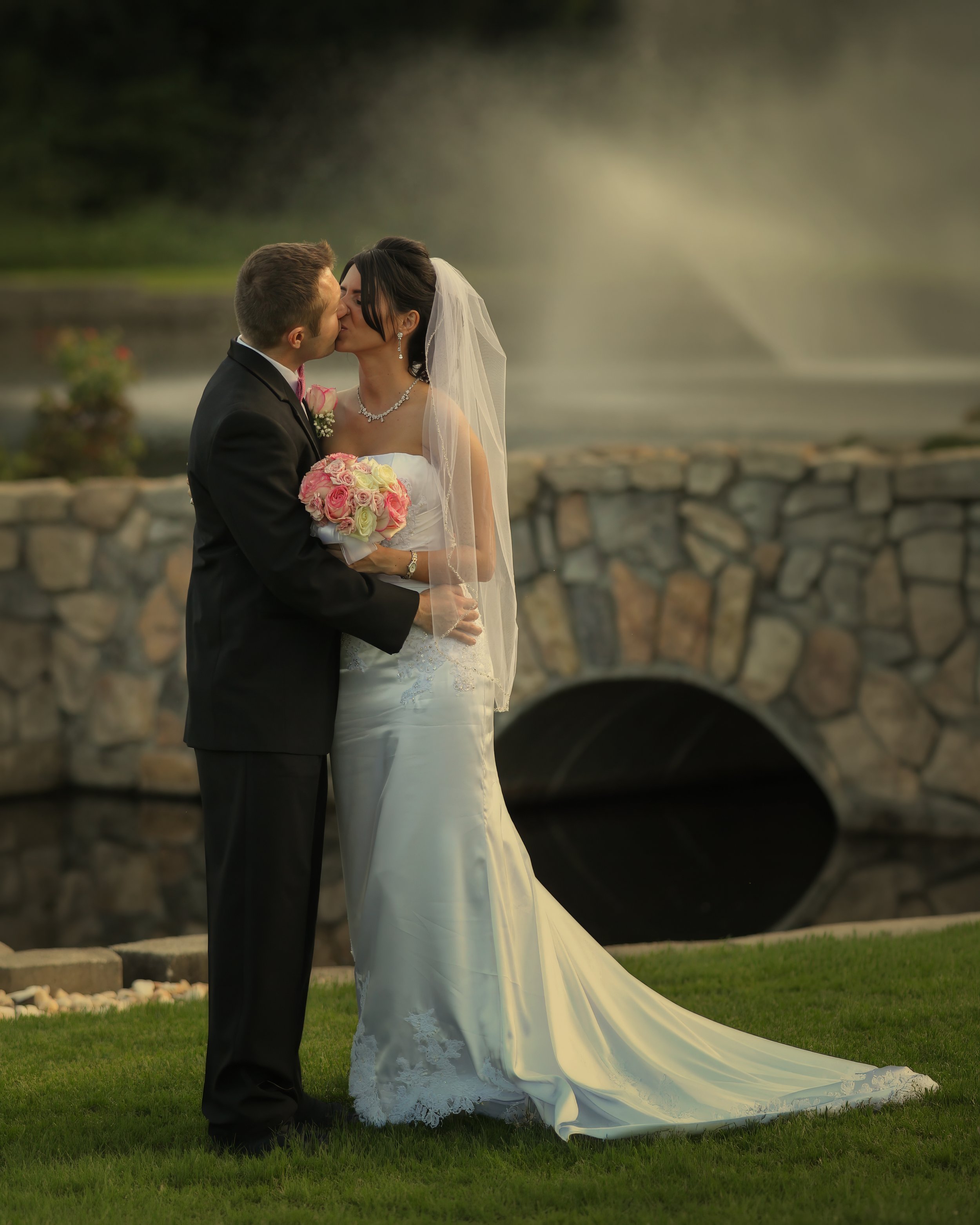 Bride and groom kiss by the lake at Aqua Turf in Southington, Connecticut