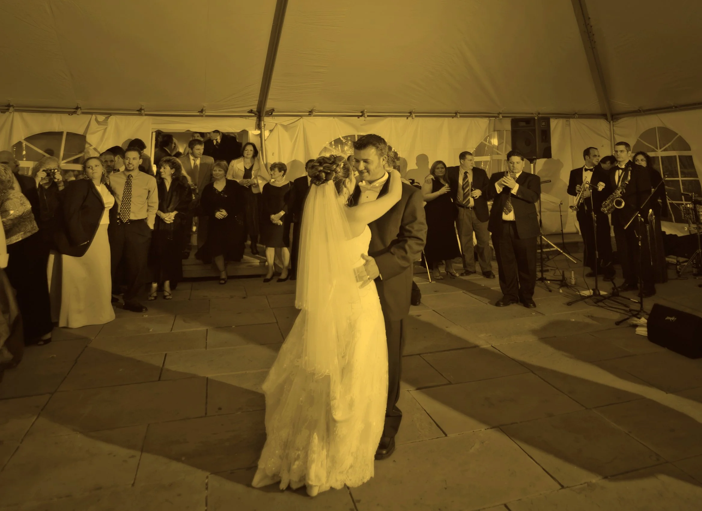 Guests dancing under a tented outdoor reception at Guilford Yacht Club at night.