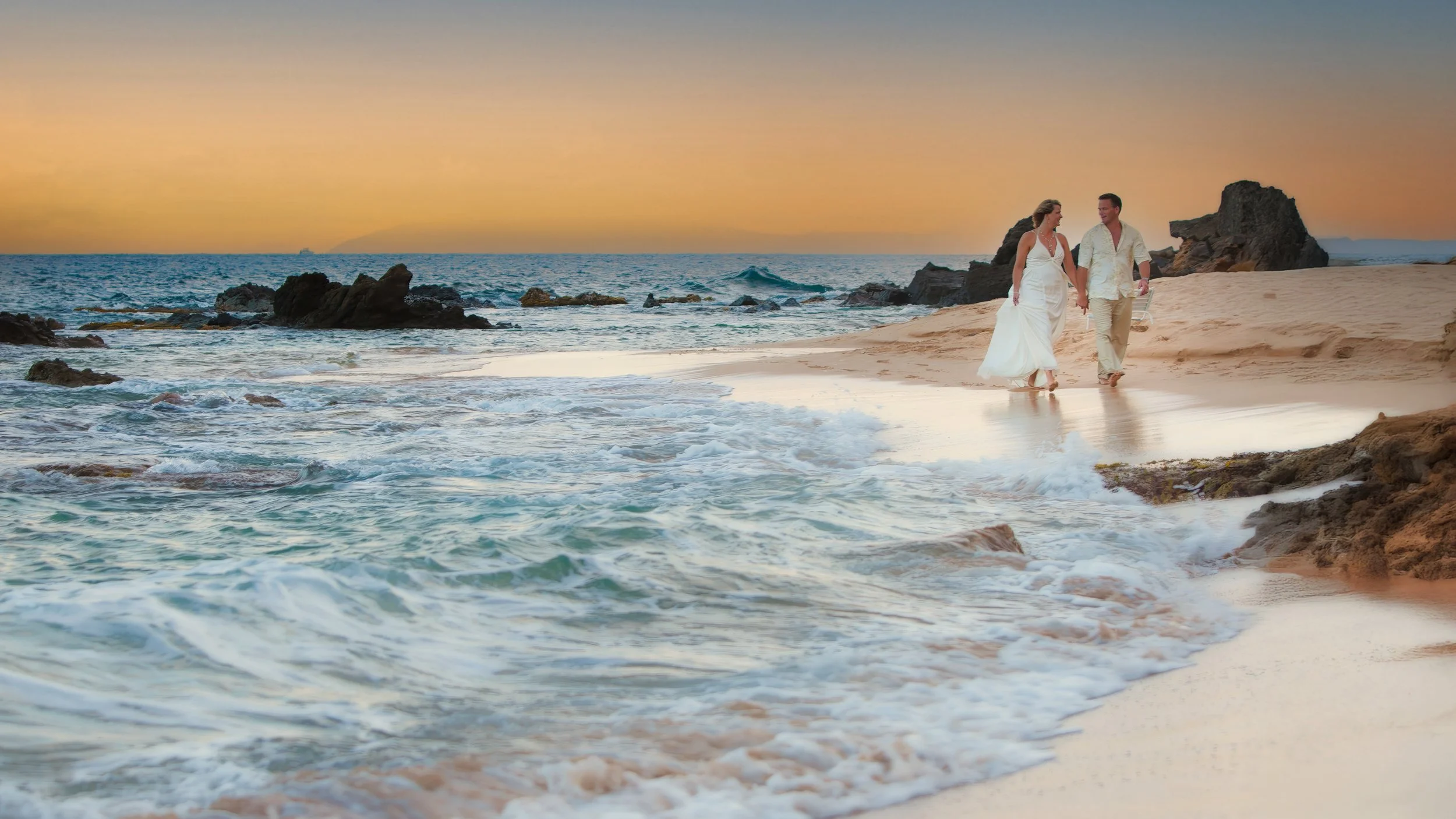 Bride and groom walking along the shoreline at Curtain Bluff in Antigua.