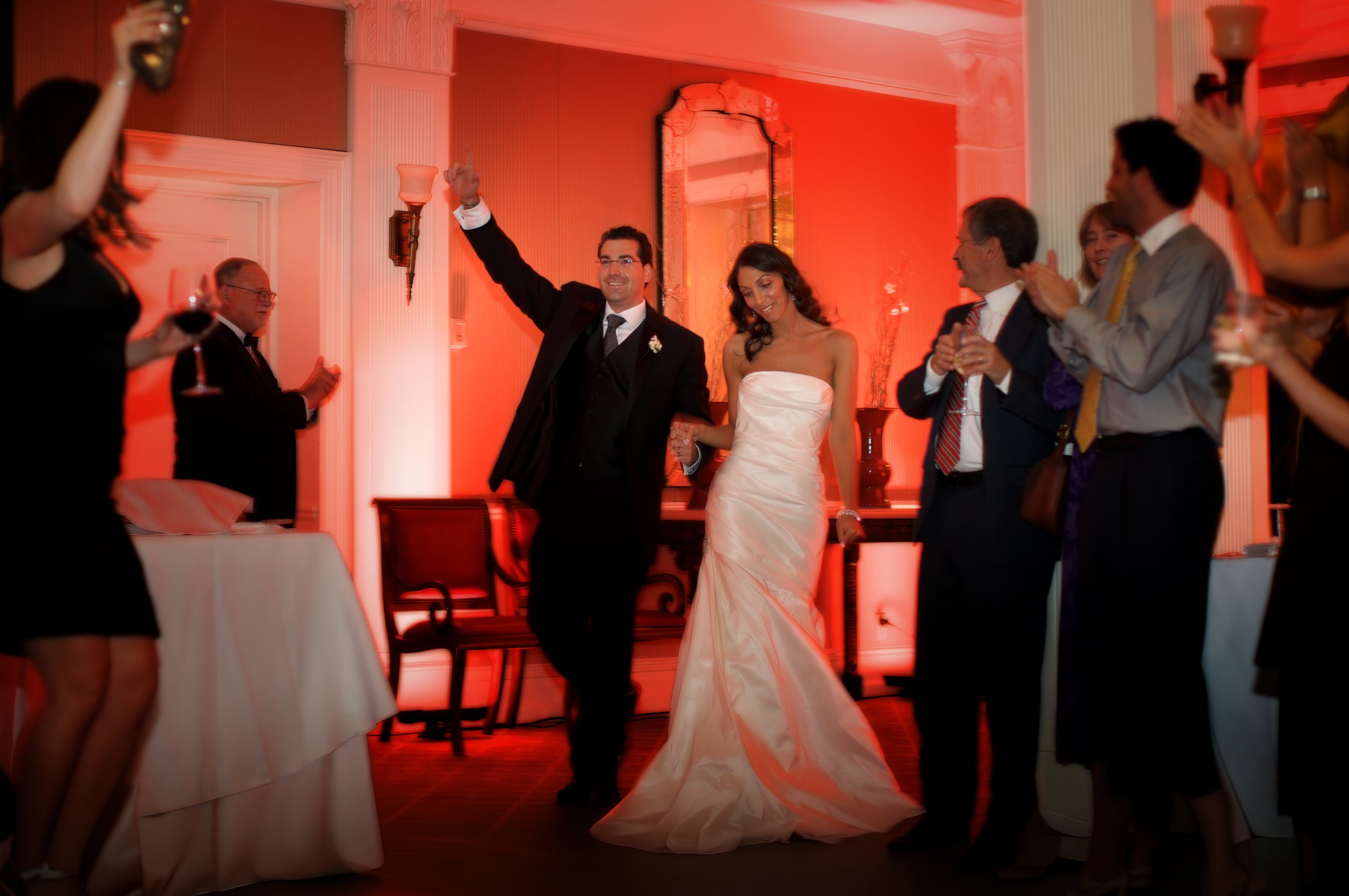 Bride and groom make a grand entrance into the ballroom, smiling widely.