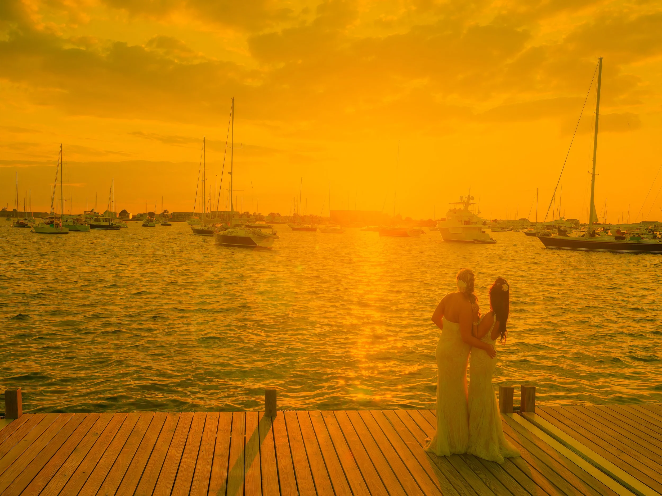 Bride and groom look out over Newport Harbor at sunset during their wedding at Newport Yachting Center.