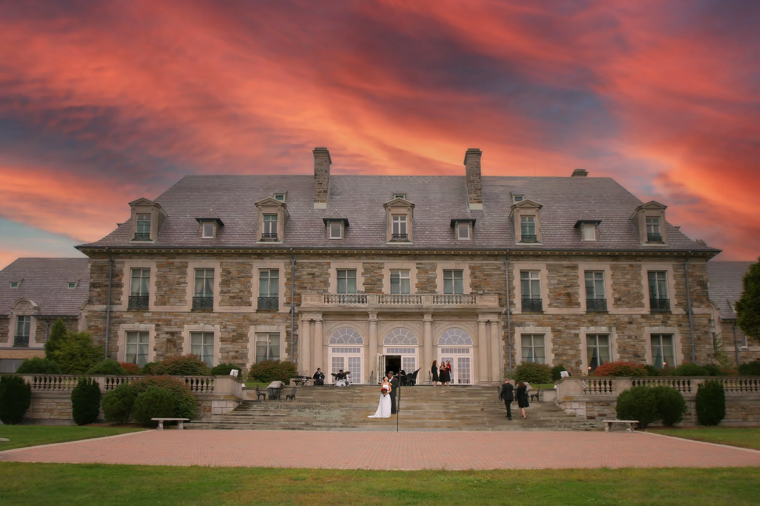 Bride and groom sharing an intimate moment beneath the grand architecture of Aldrich Mansion in Rhode Island.