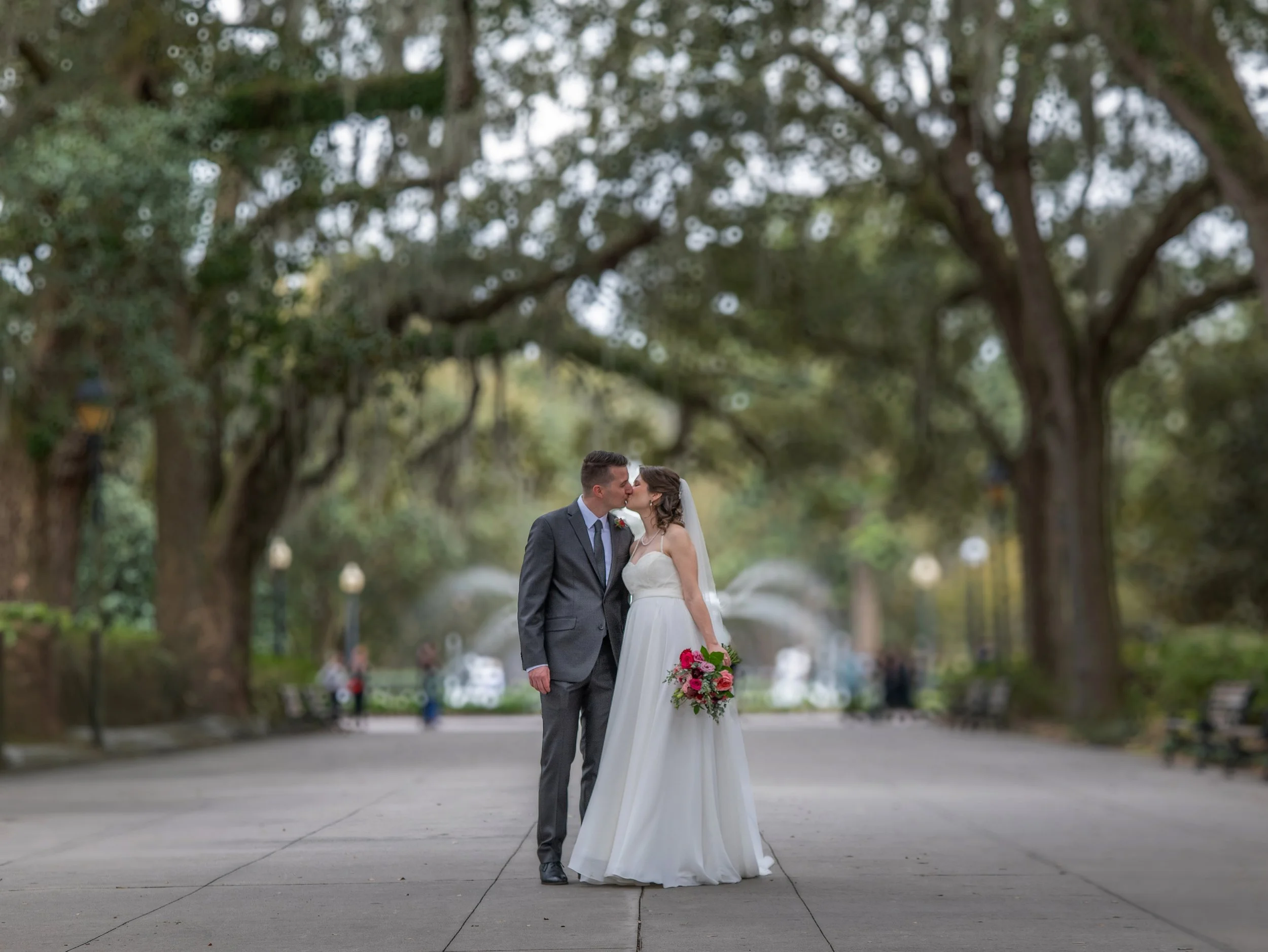 Bride and groom kiss on the promenade leading to the Forsyth Park fountain in Savannah.