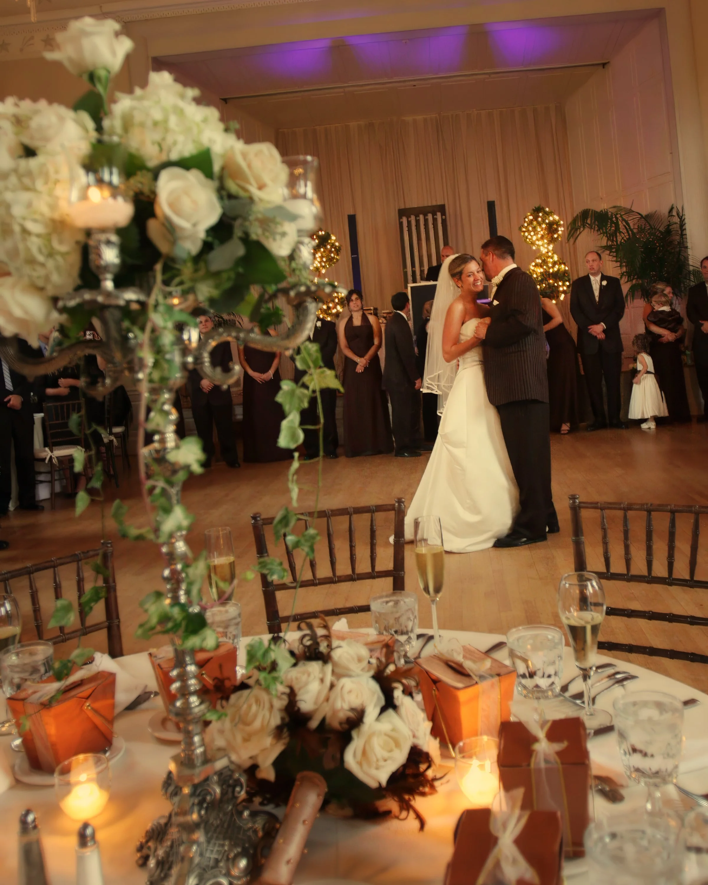 Bride and groom enjoy their first dance framed by elegant tablescapes in the New Haven Lawn Club ballroom.