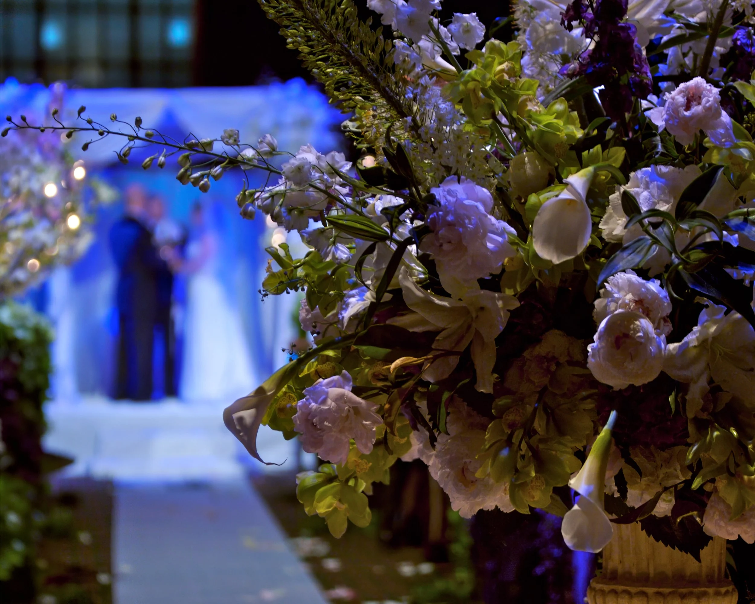 Bride and groom exchange vows beneath lavish floral arrangements lining the ceremony aisle at Cipriani 42nd Street in New York City.