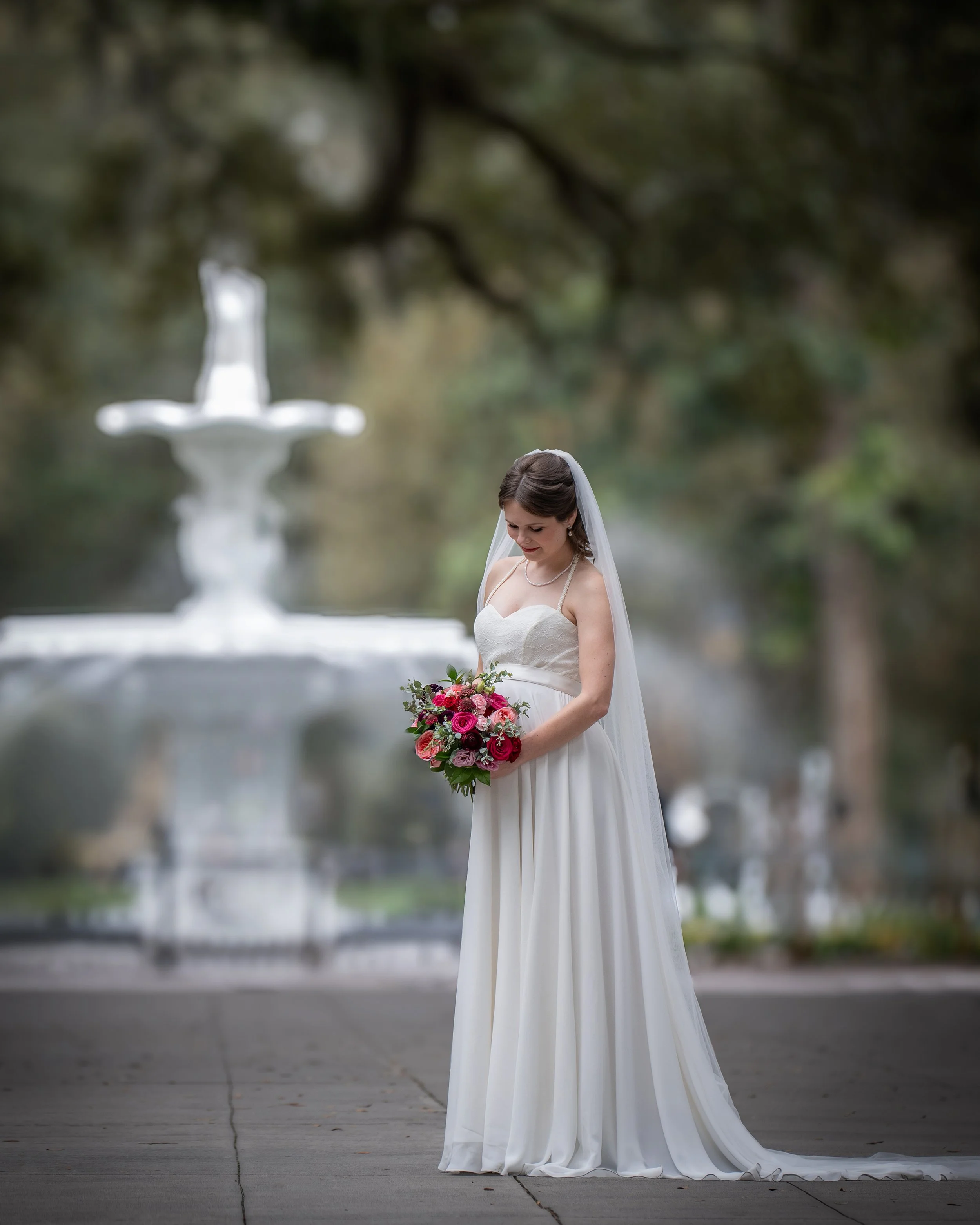 Daniella holds her colorful bridal bouquet beside the Forsyth Park Fountain during her Savannah micro wedding portrait session.