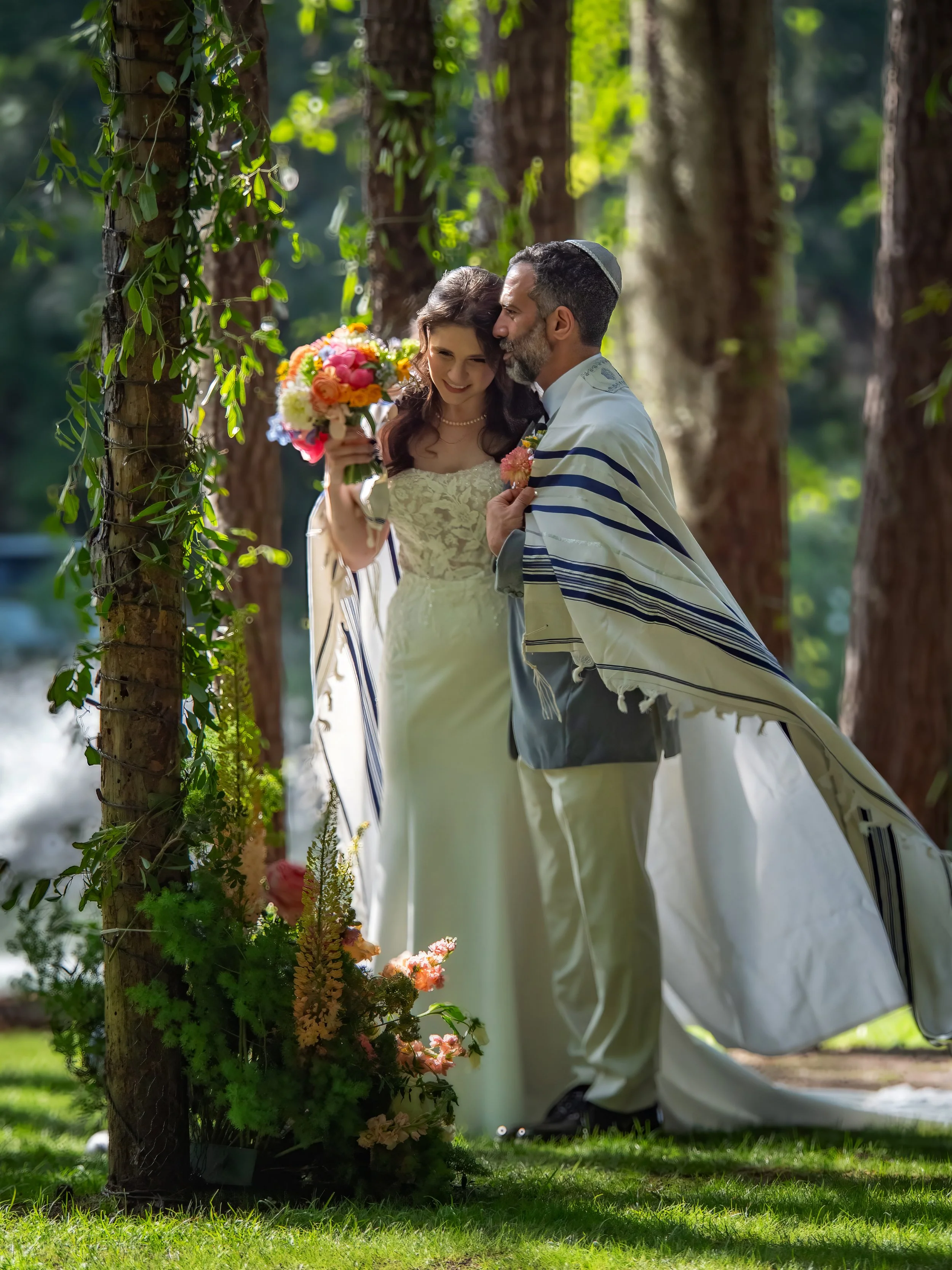 Bride and groom sharing an intimate wedding ceremony moment beneath tall pines and live oaks at The Mackey House in Savannah, Georgia.