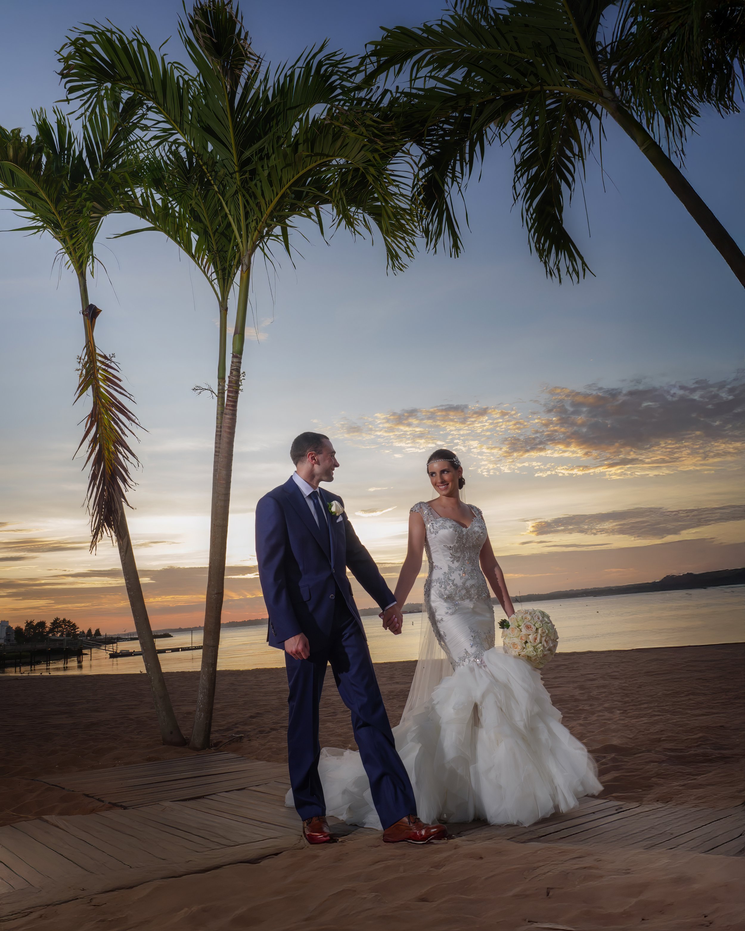 Bride and groom take a sunset walk on the beach at Anthony's Ocean View.